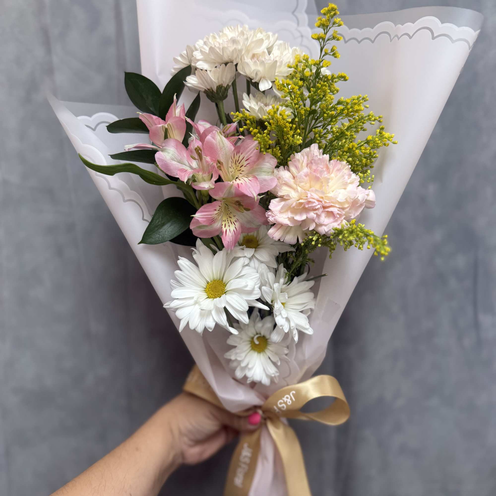 Pink and white daisies with a pink carnation and purple accents, wrapped