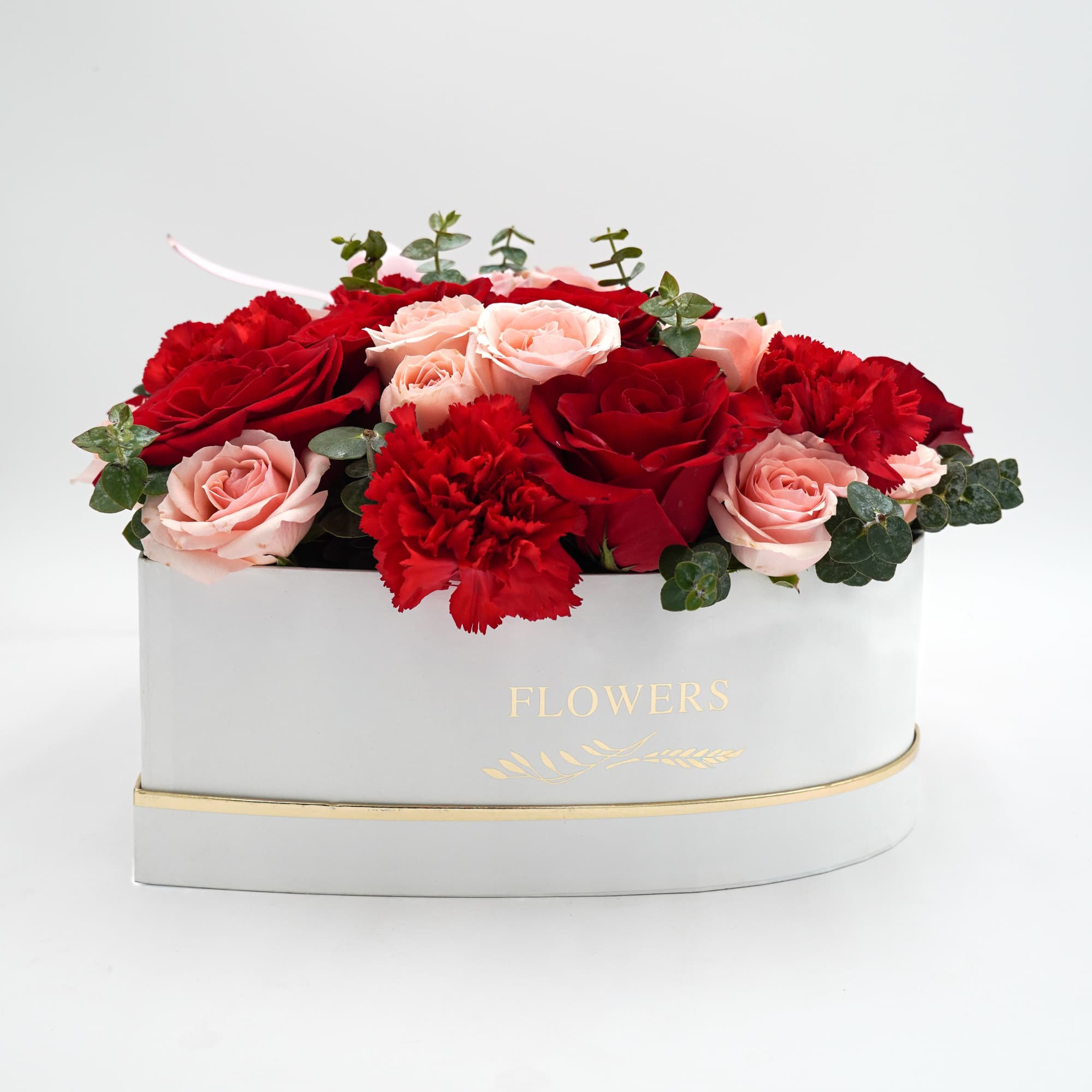 This romantic heart-shaped arrangement features red and pink roses accented with lush