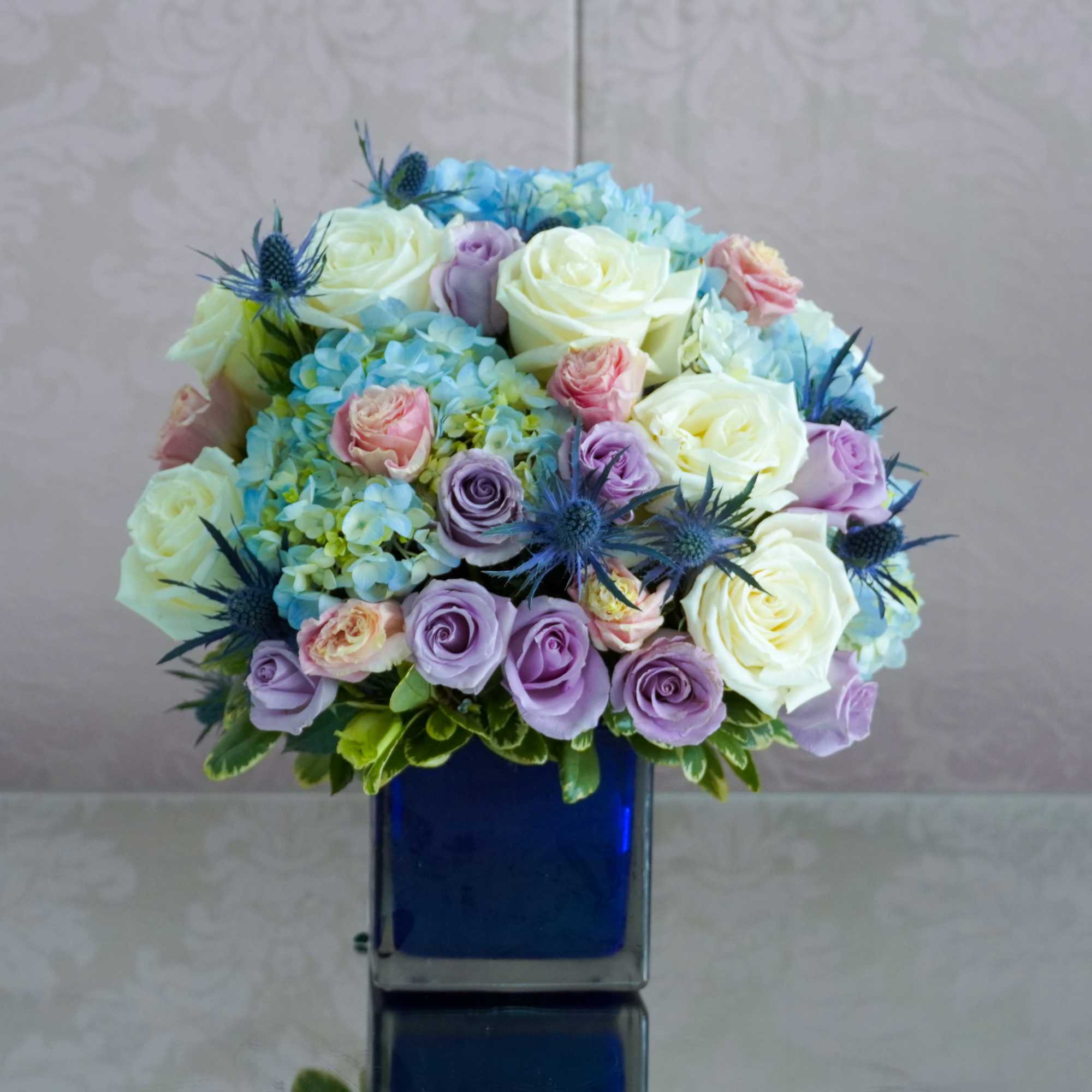 Cream-white roses and pale blue hydrangeas form a soft, romantic dome in
