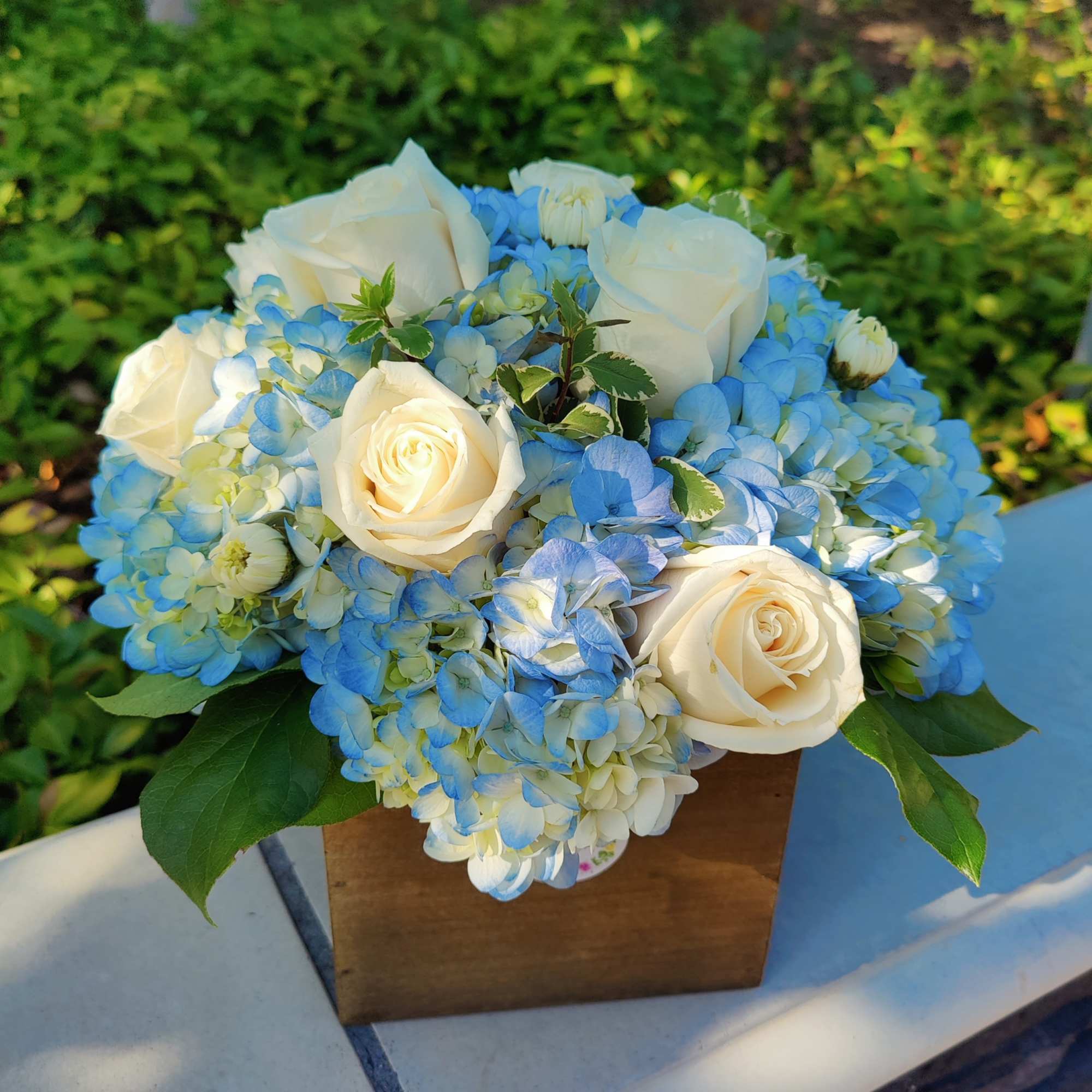 Blue hydrangea and white rose bouquet in a wooden box