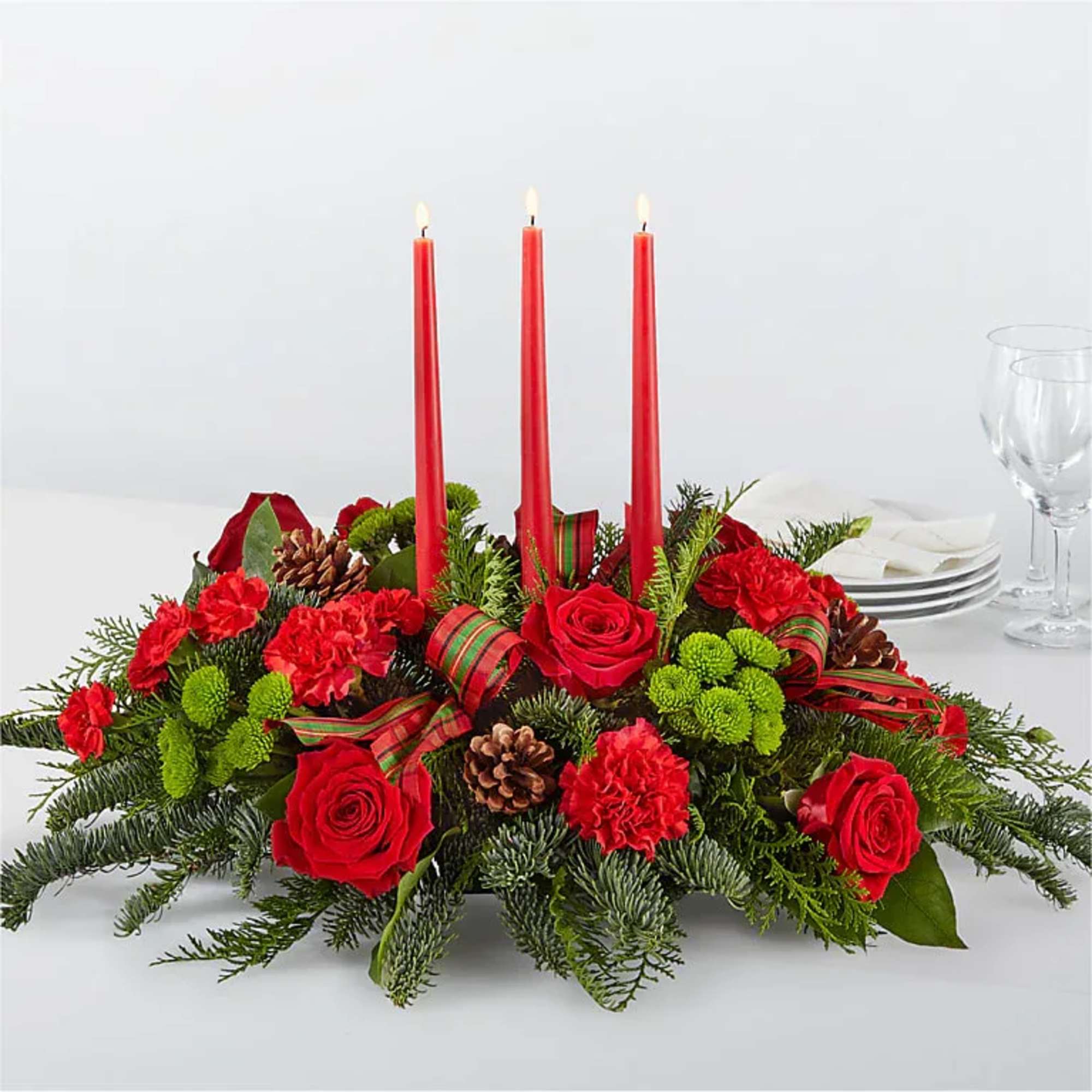 Holiday centerpiece with red roses, carnations, and three red taper candles