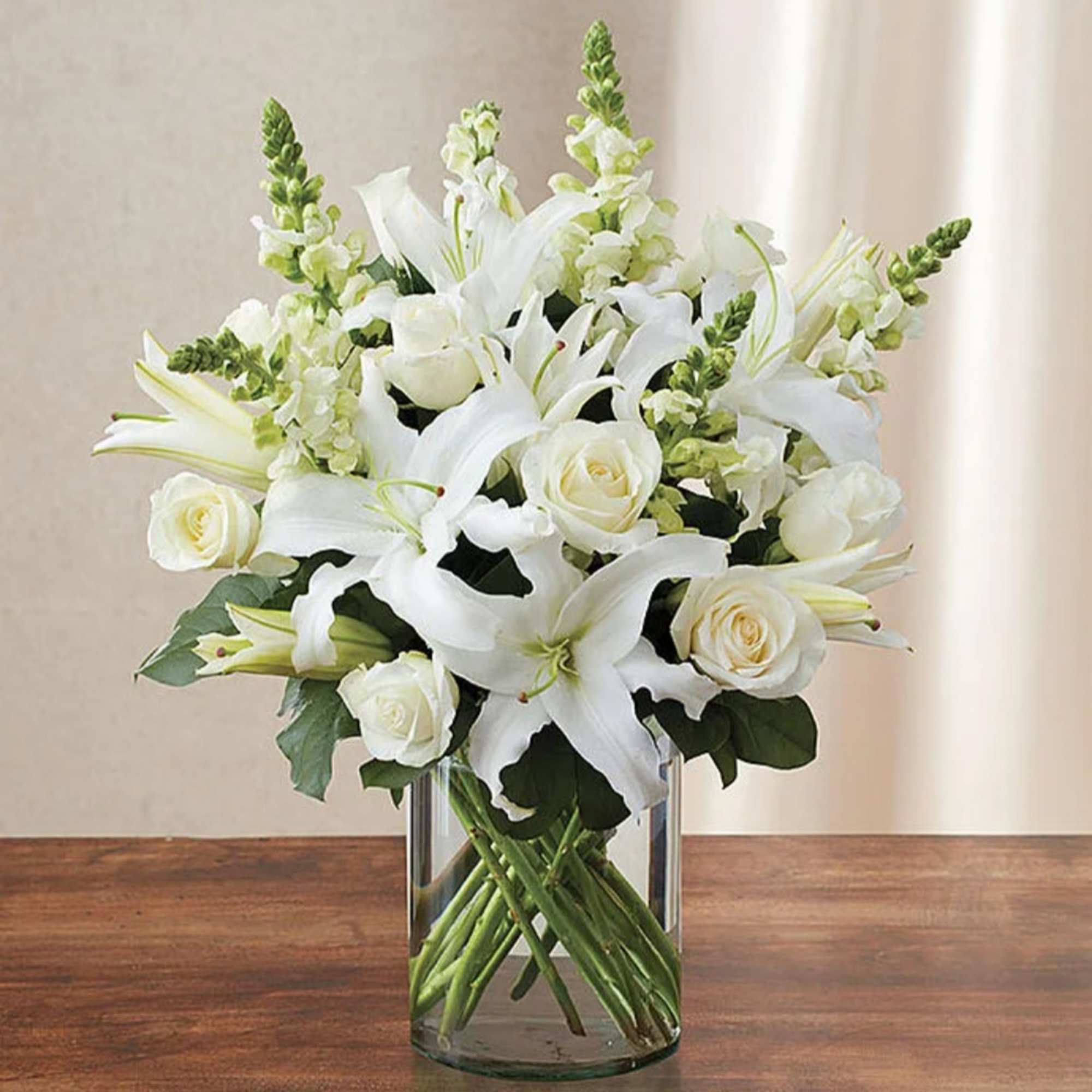 White lilies and roses arranged in a clear glass vase