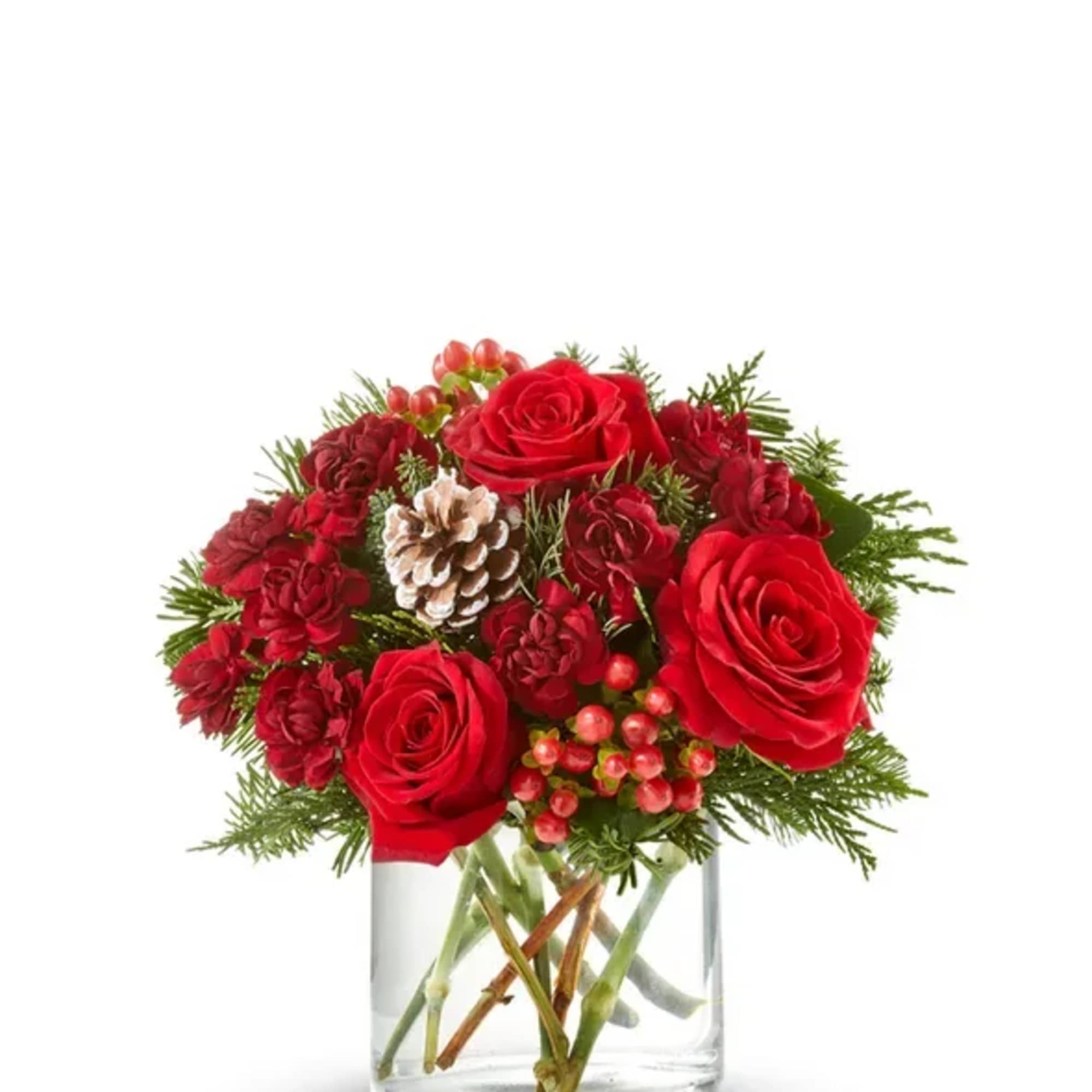 Red roses and carnations in a clear glass vase with pinecones and berries