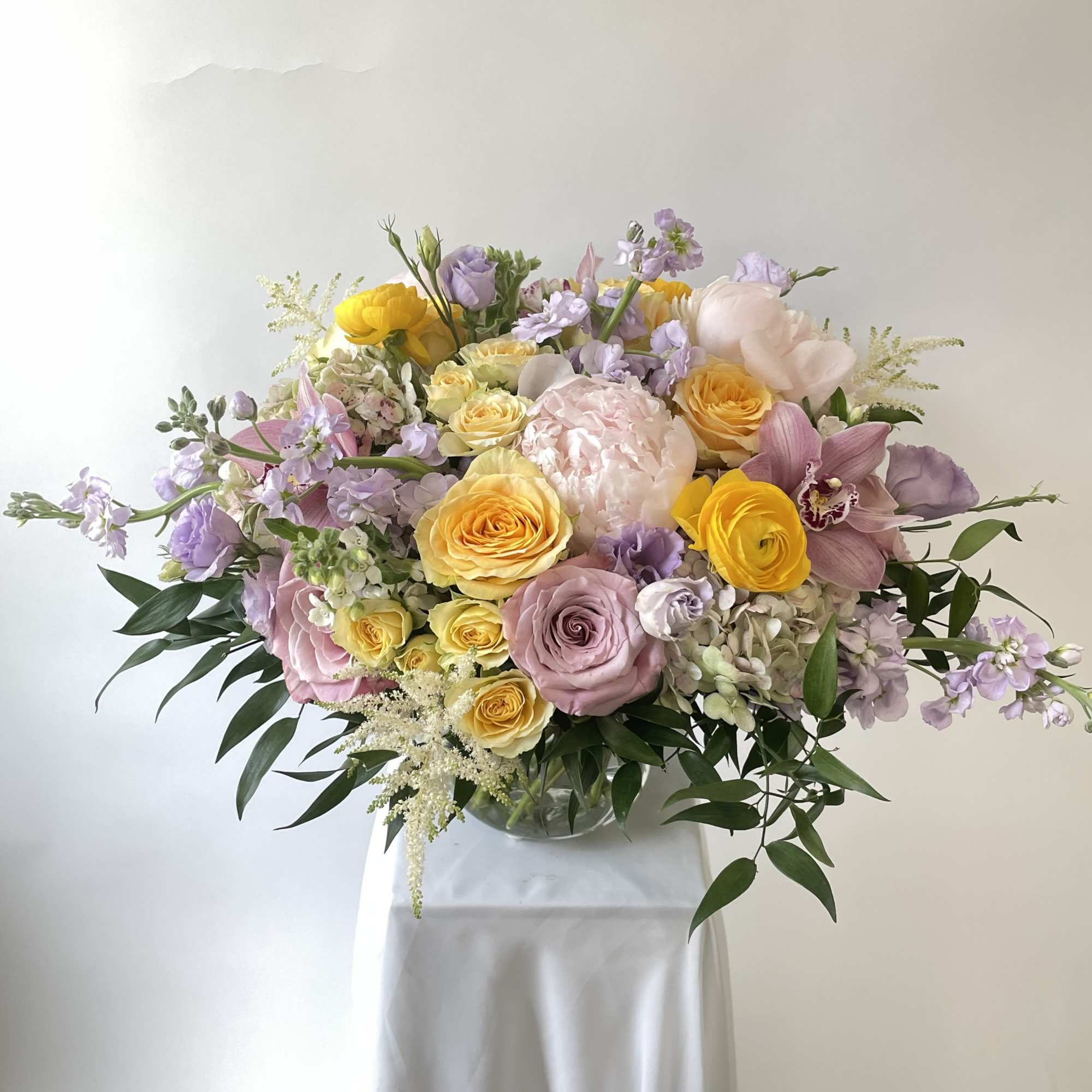 Pastel bouquet of roses, orchids, and lilac flowers in a glass vase