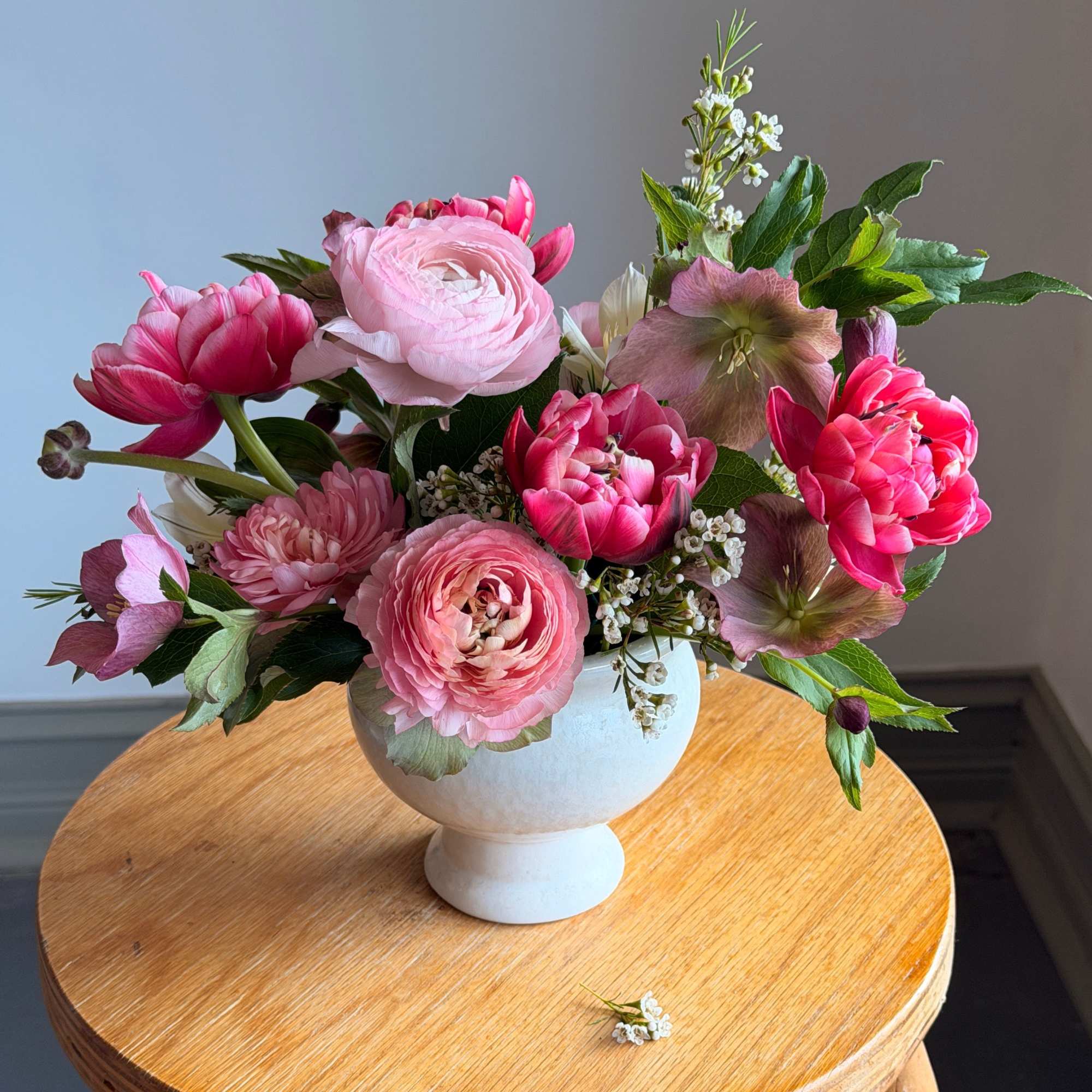Pink floral arrangement in a white pedestal vase