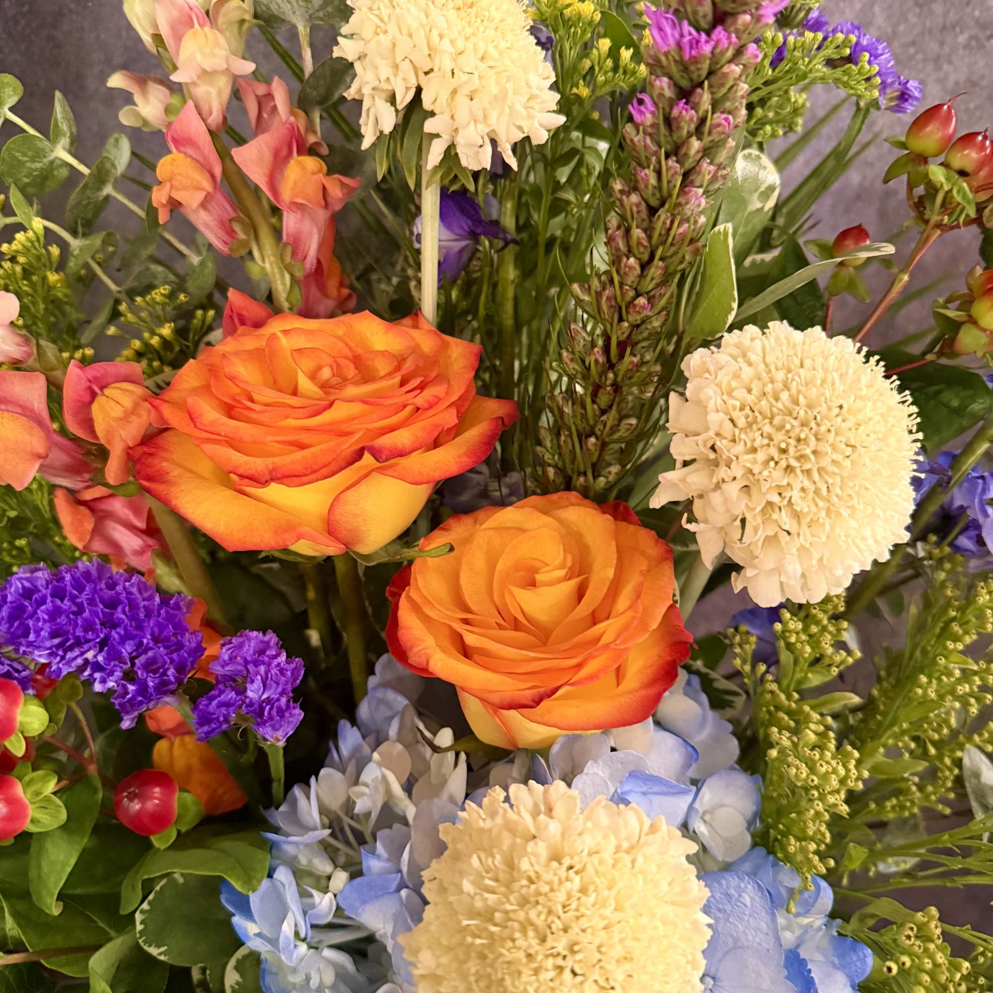 This stunning tall modern arrangement filled with vibrant colors such as red