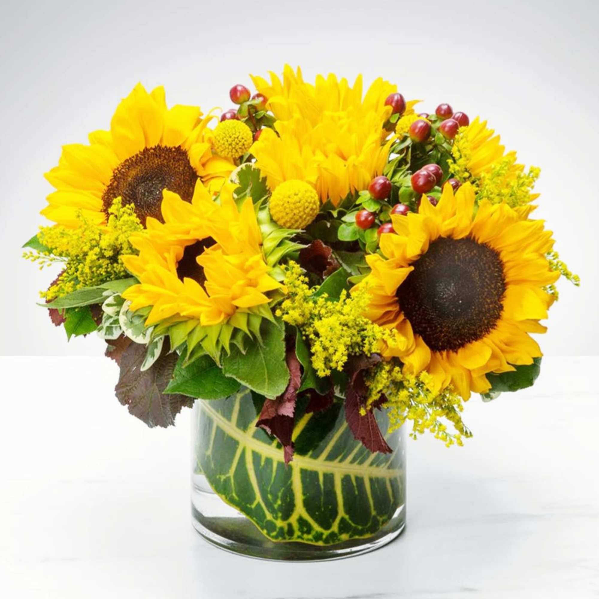 Sunflower arrangement in a clear glass vase with yellow filler flowers