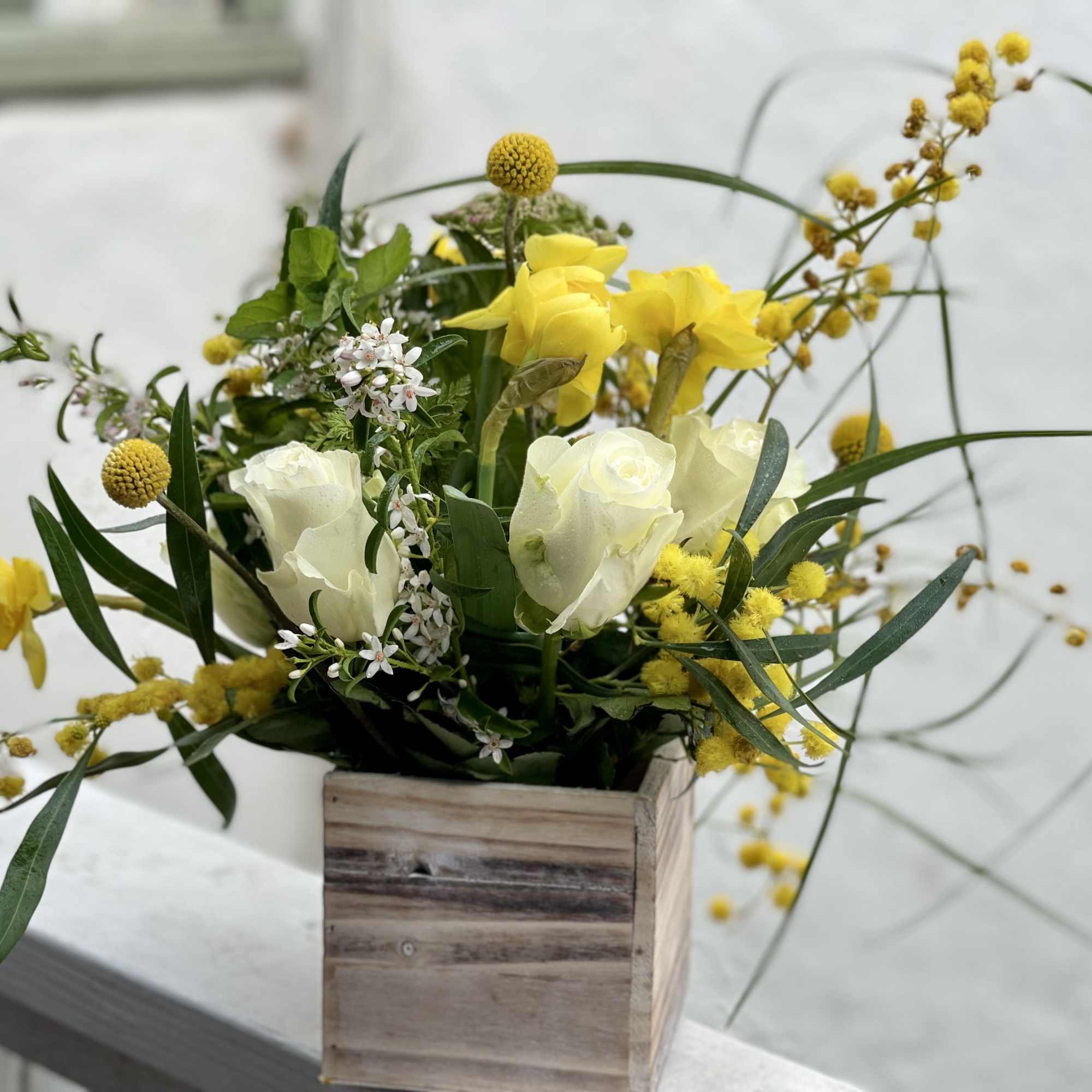 Yellow and white floral arrangement in a wooden box