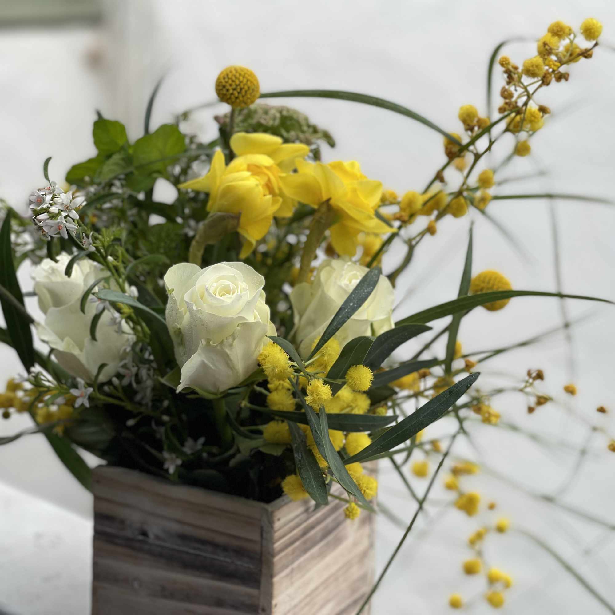 Yellow and white flowers arranged in a wooden box