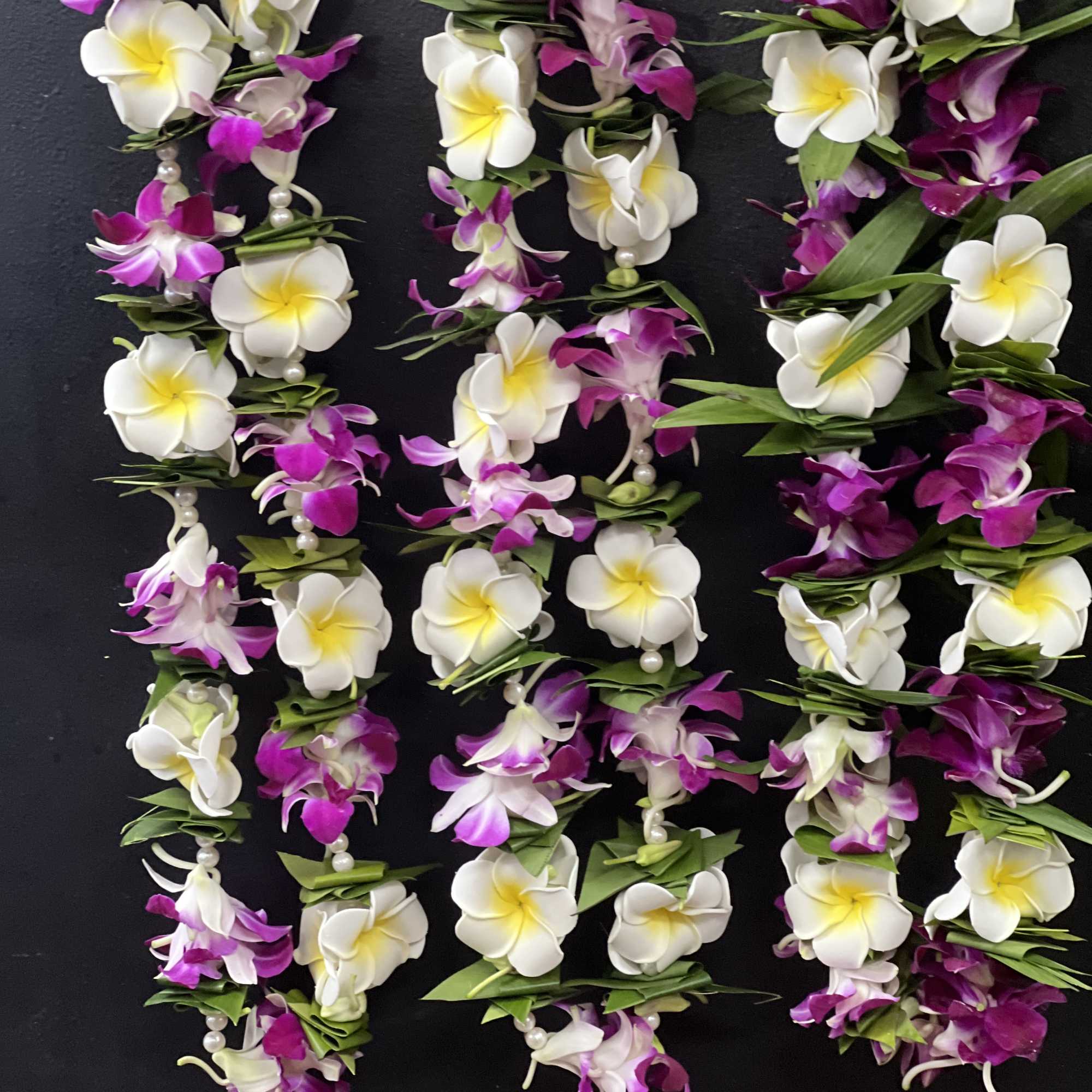 Garlands of white and purple flowers with pearl accents on a dark background
