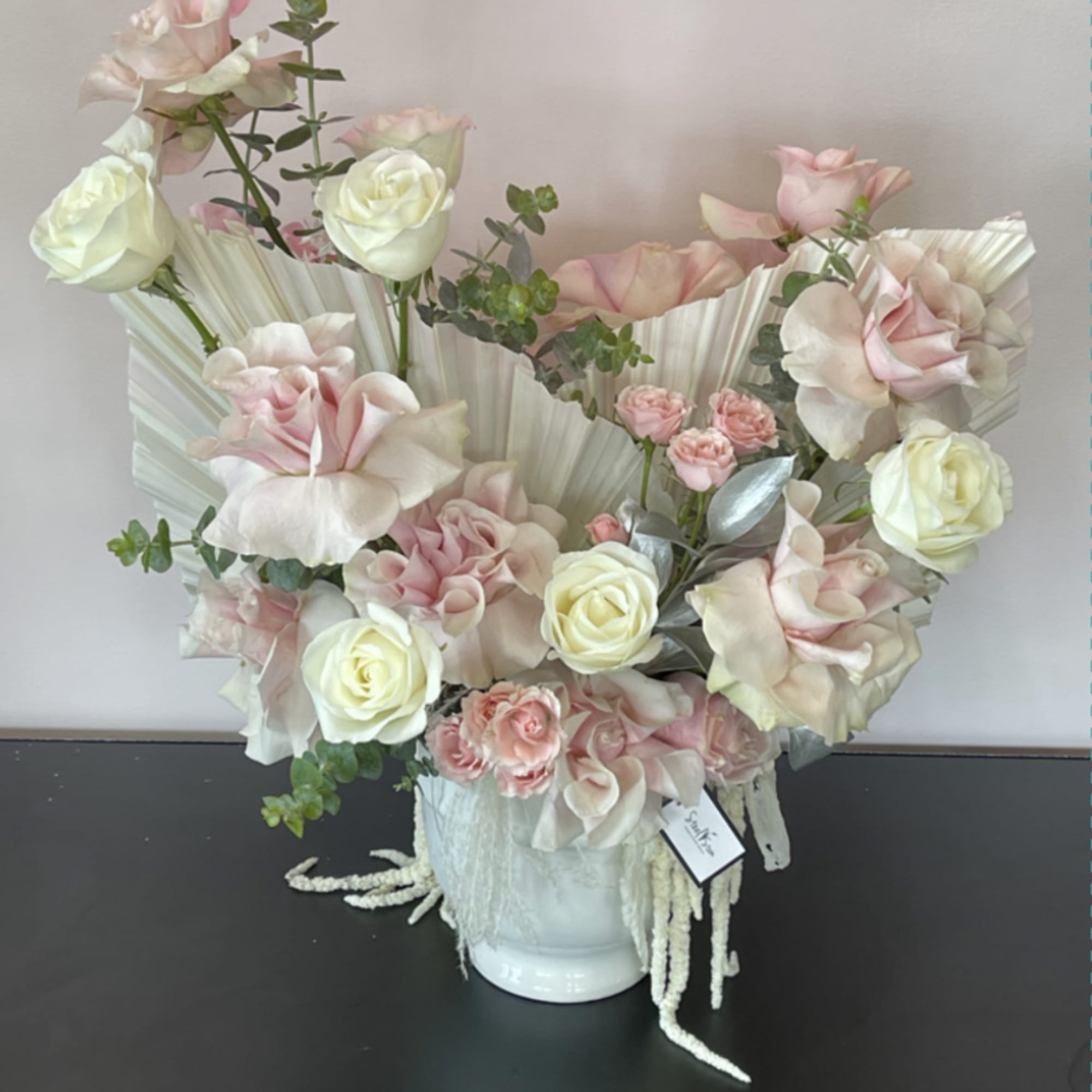 Pink and white rose arrangement in a white vase