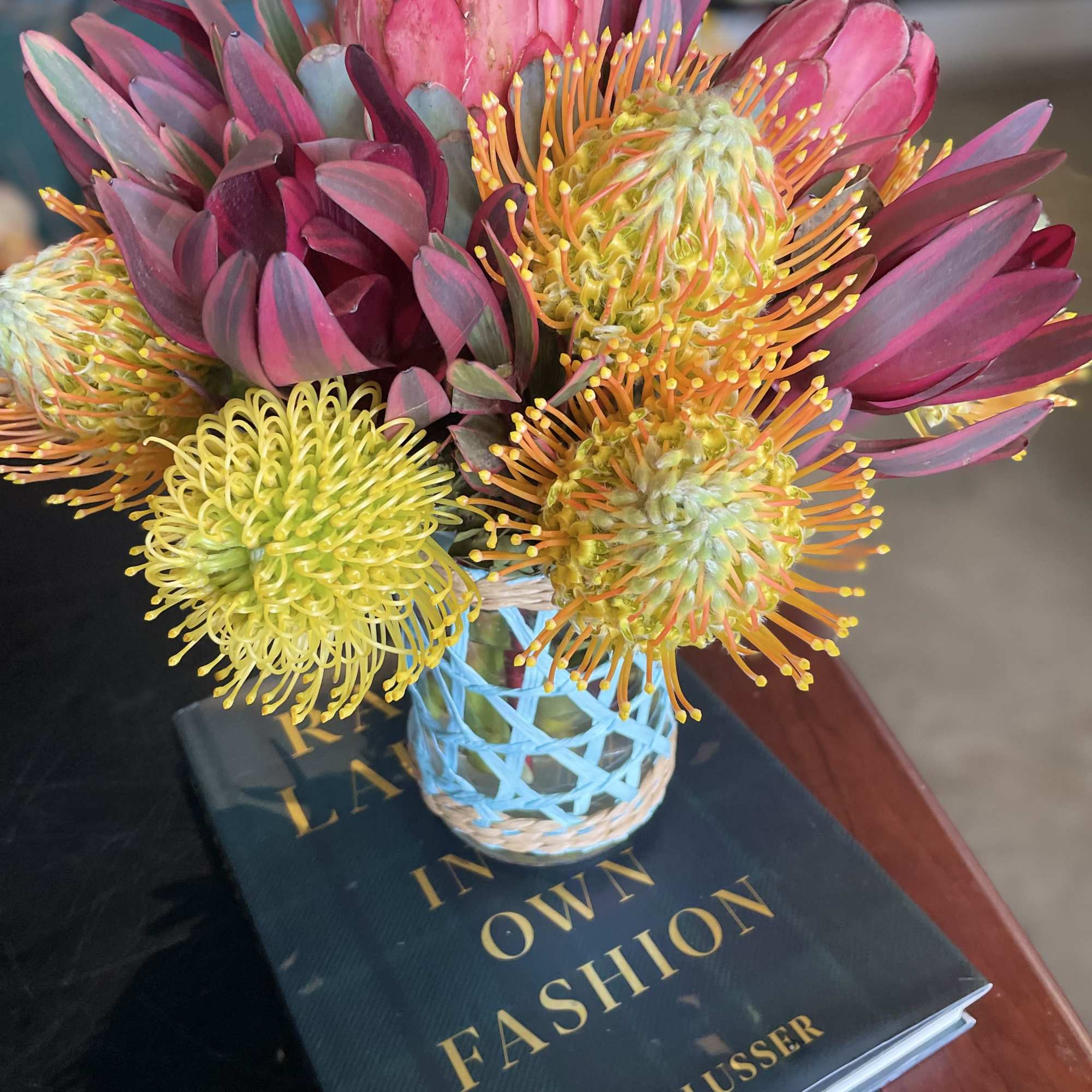 Bright pink and yellow protea bouquet in a small wrapped vase
