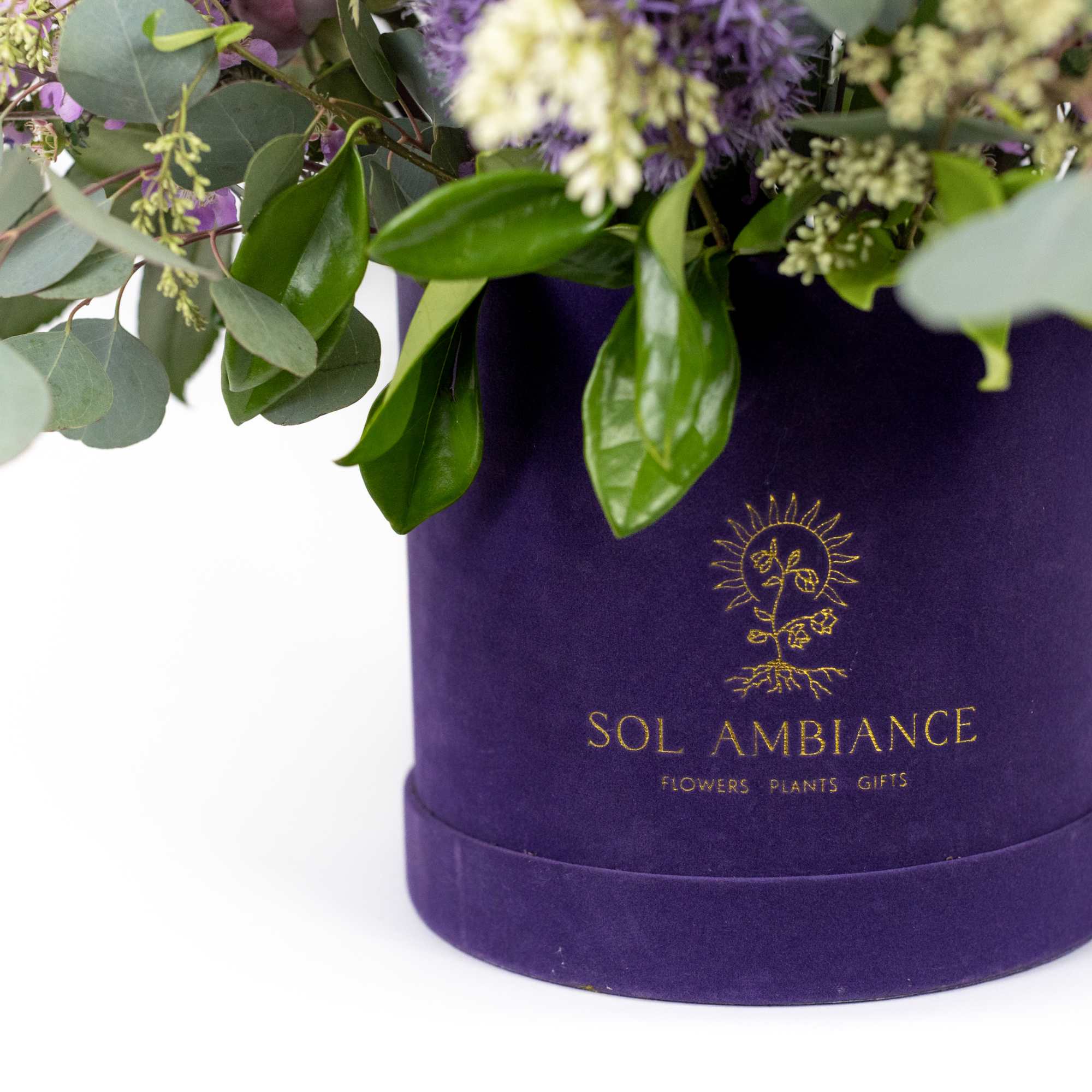 Mixed bouquet in a purple hatbox with eucalyptus and purple blooms