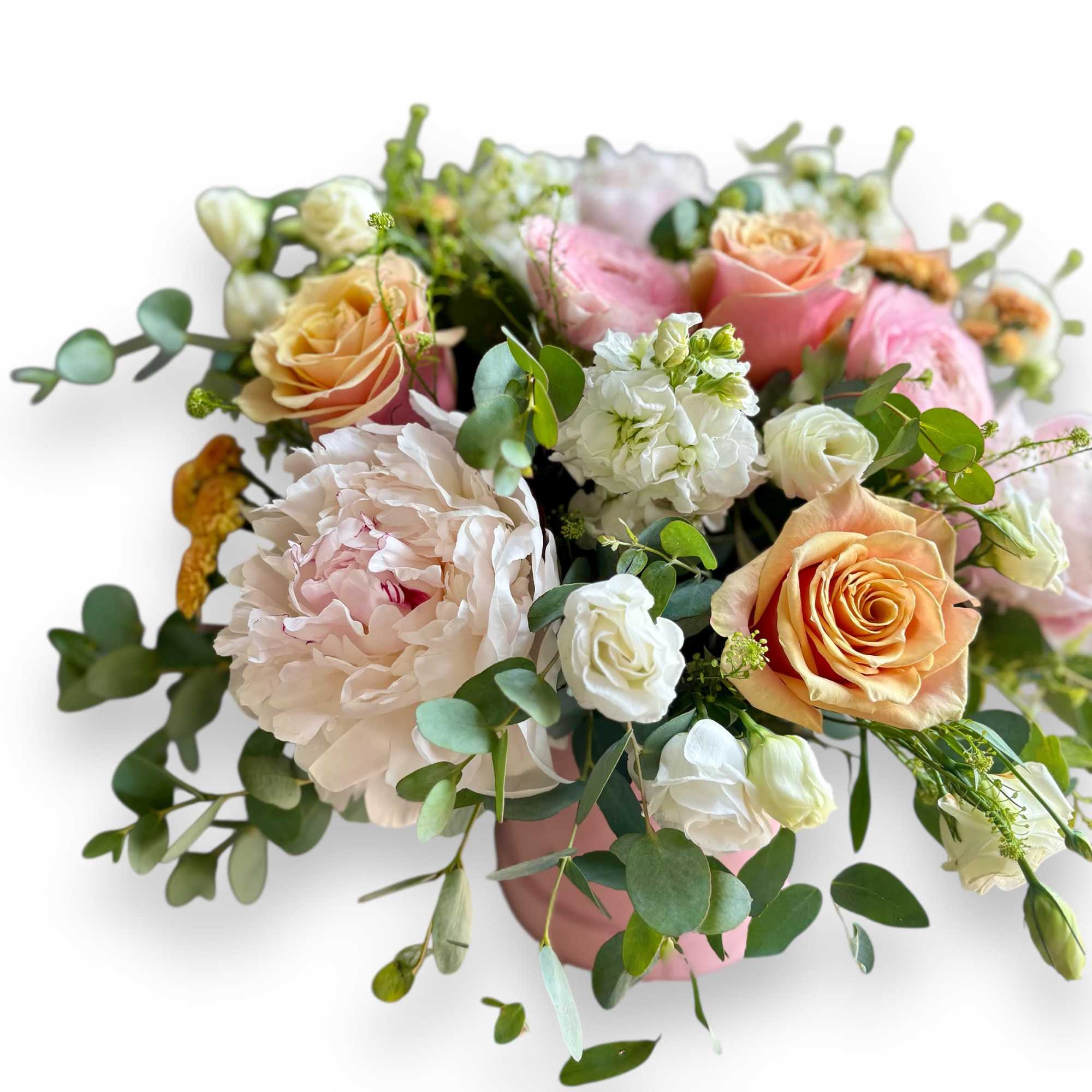 Blush peonies, peach and pink roses, and white blooms arranged in a pink vase