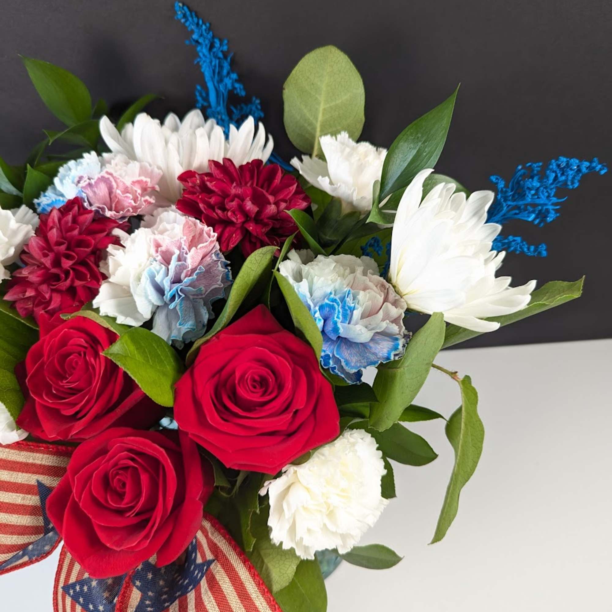 Bouquet of red roses, white daisies, and carnations with patriotic ribbon
