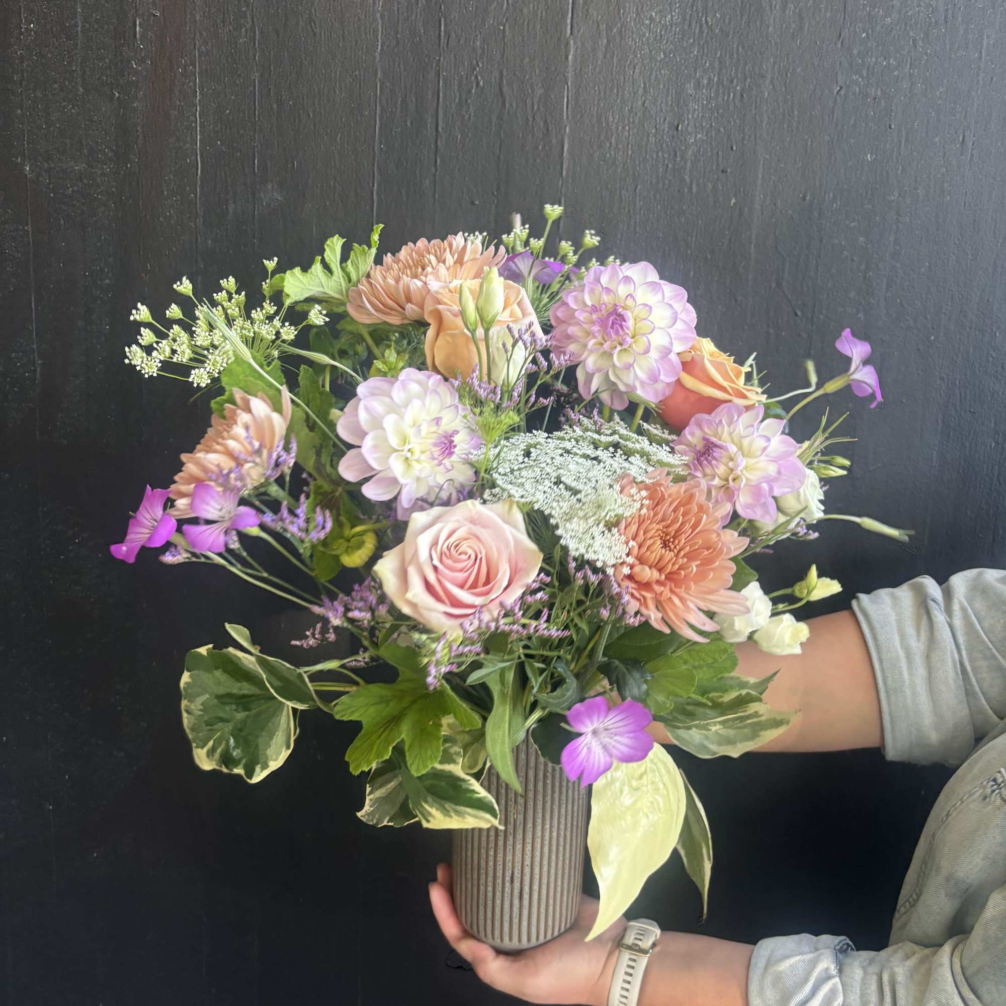 This weekly seasonal arrangement showcases lavender dahlias, peach roses, and Queen Anne's