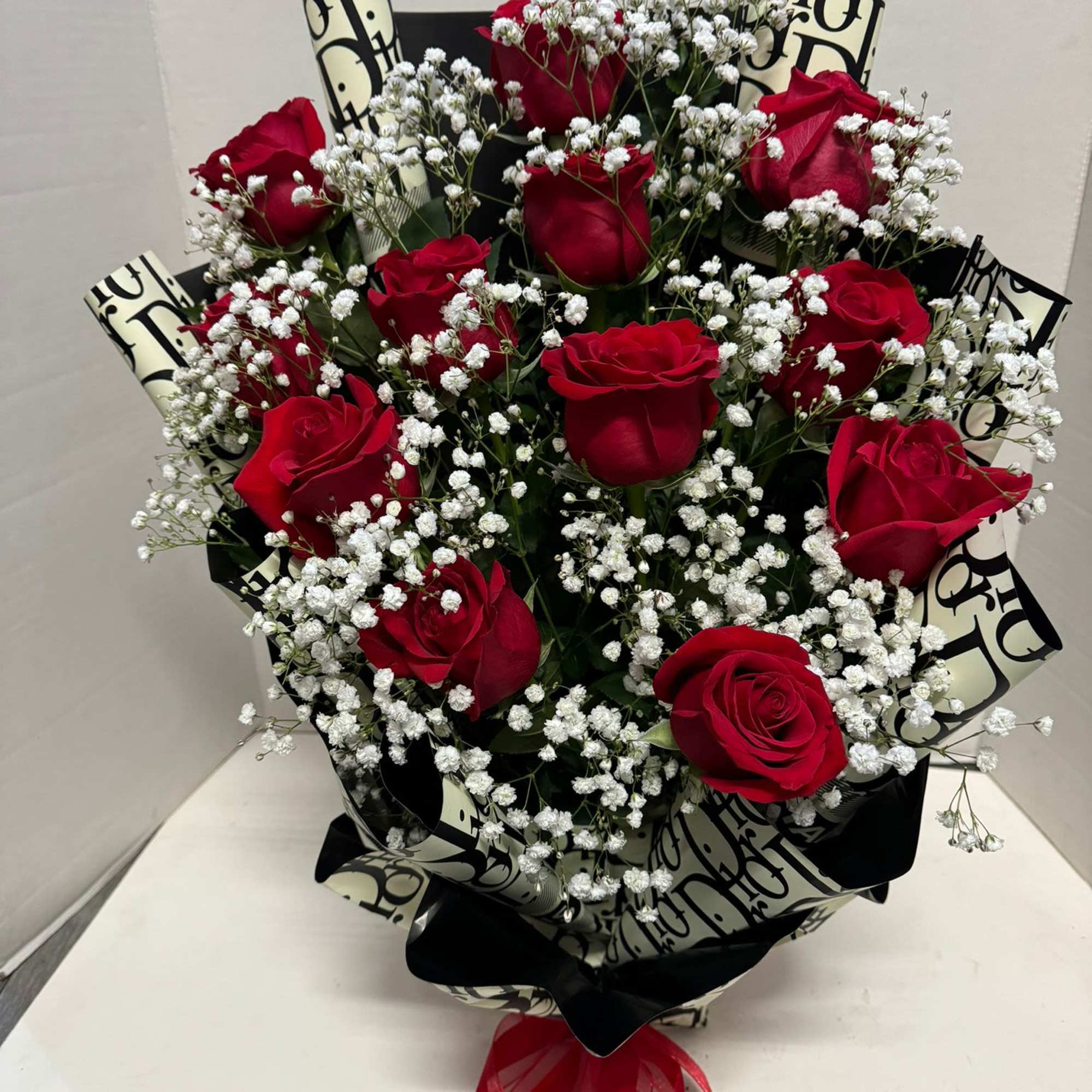 Bouquet of red roses with white baby's breath and black patterned wrap