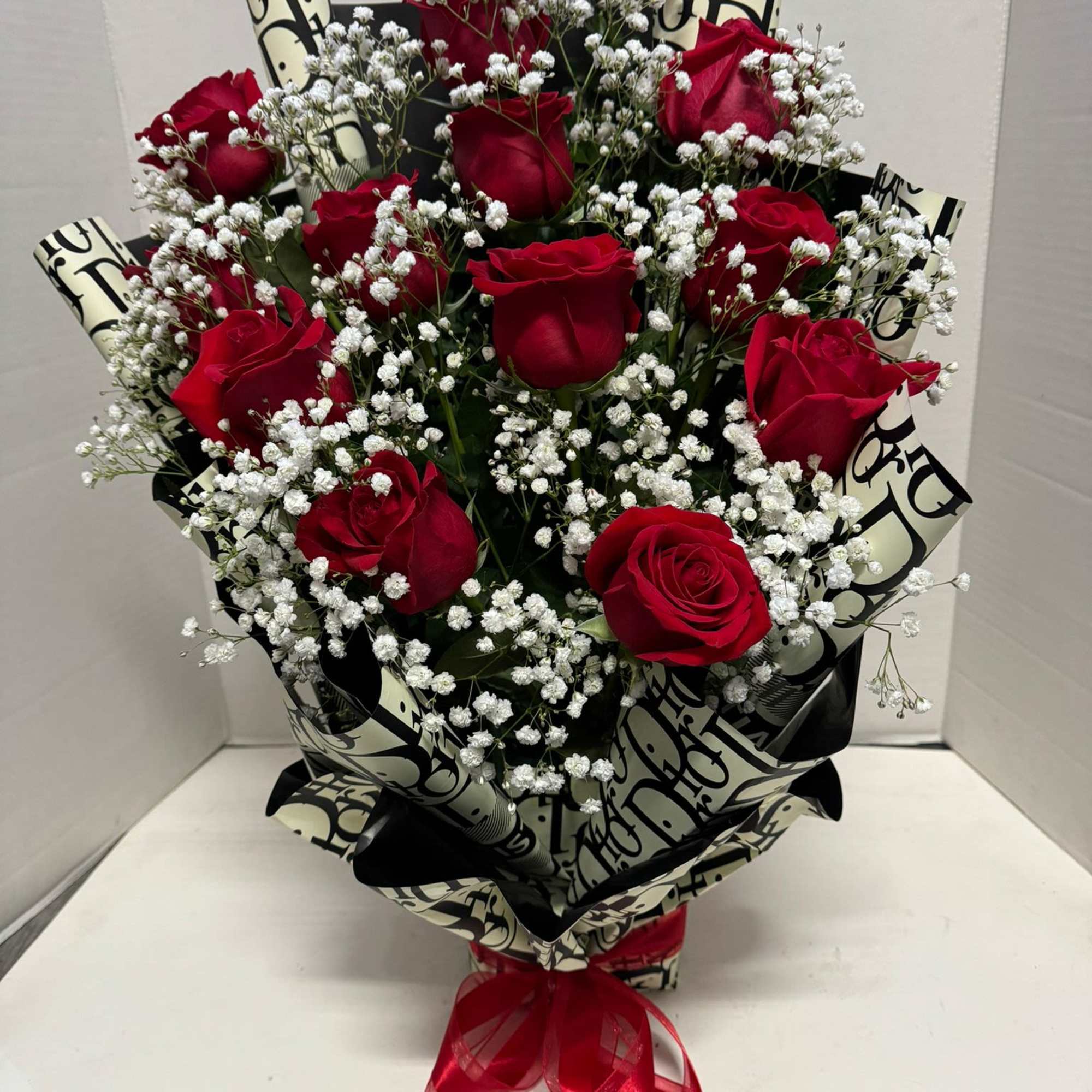 Bouquet of red roses and white baby's breath wrapped in black-and-cream paper
