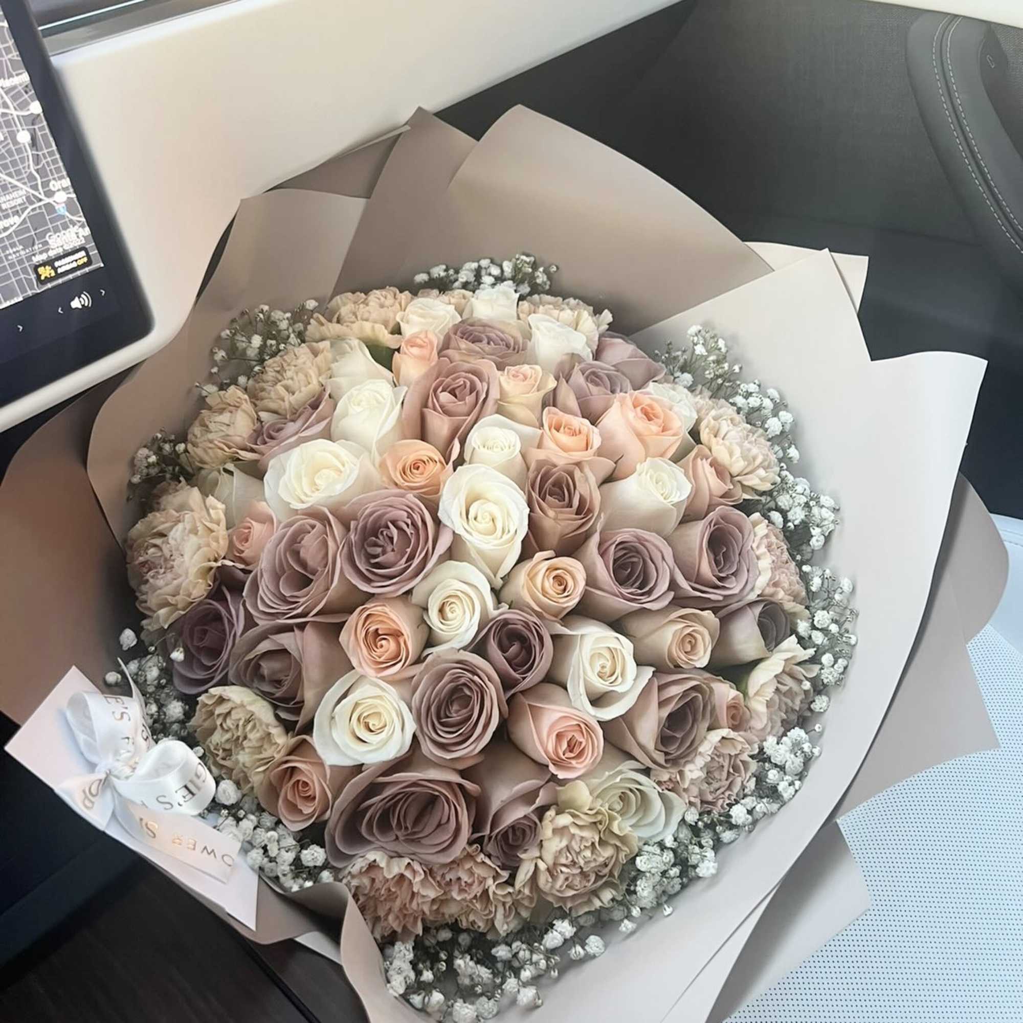 Large bouquet of blush, cream, and mauve roses wrapped in taupe paper