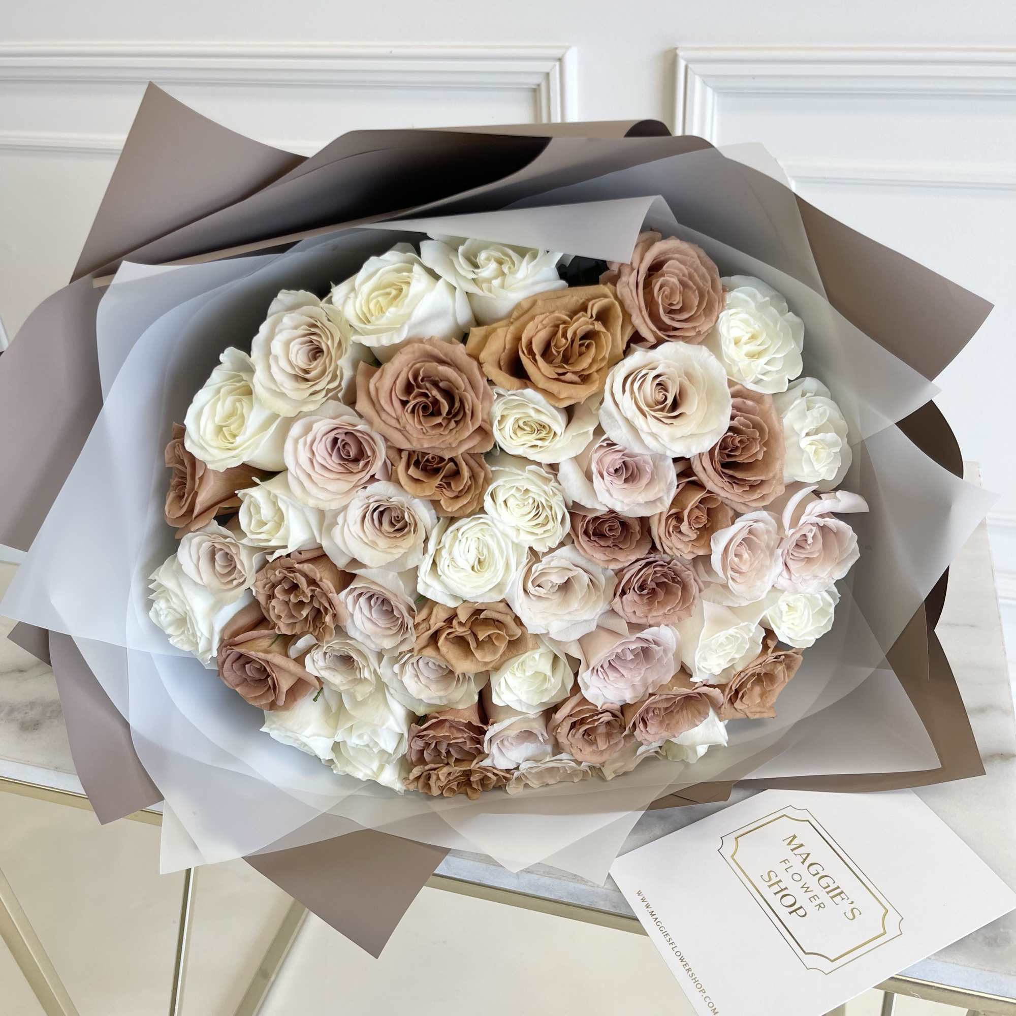 Large bouquet of cream and blush roses wrapped in brown and white paper
