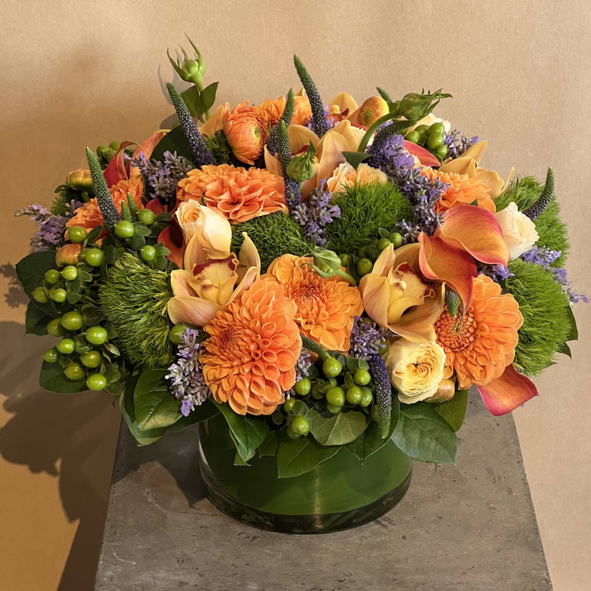 Orange and peach flowers arranged in a green glass vase