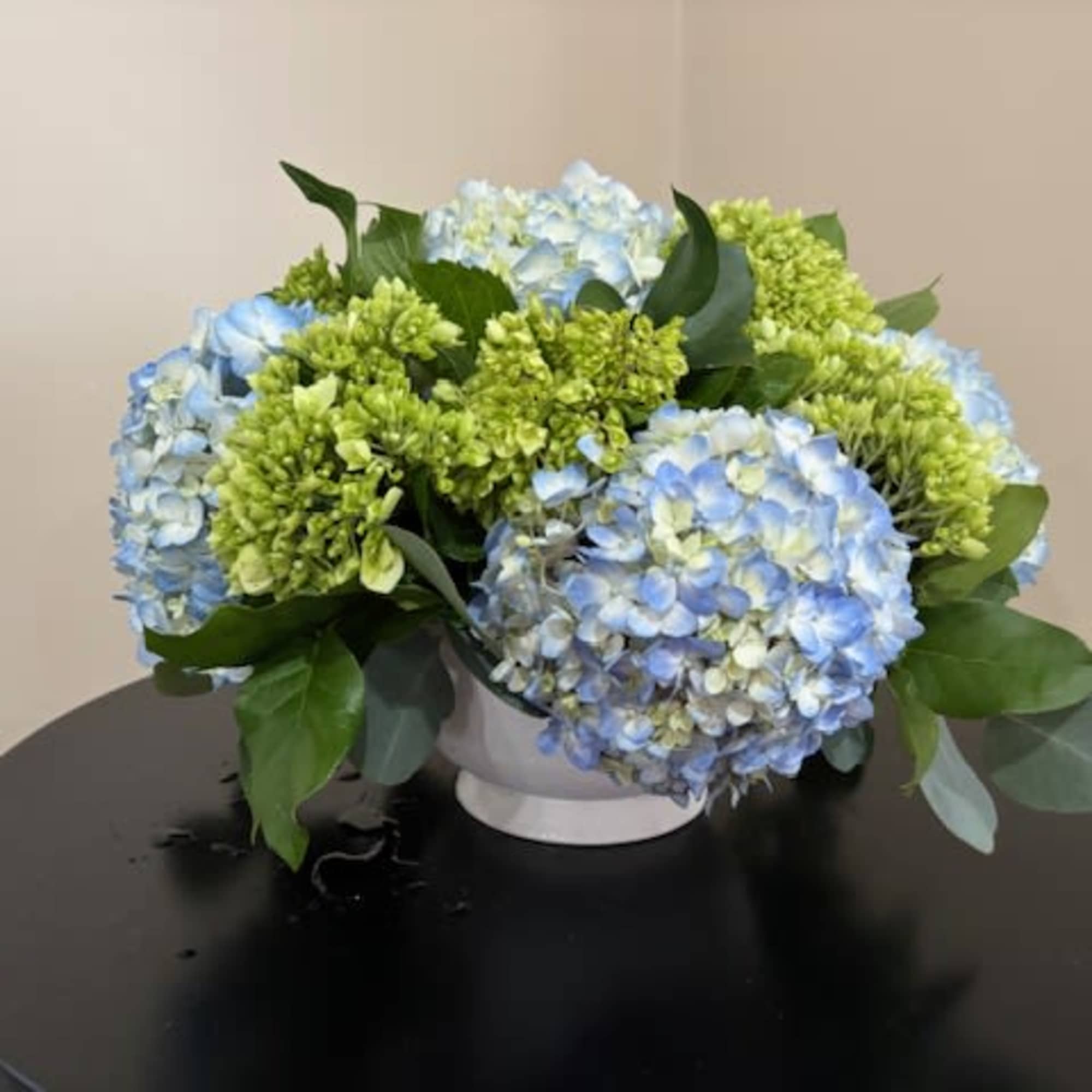 Rounded clusters of blue and chartreuse-green hydrangeas form a soft, dome-shaped centerpiece