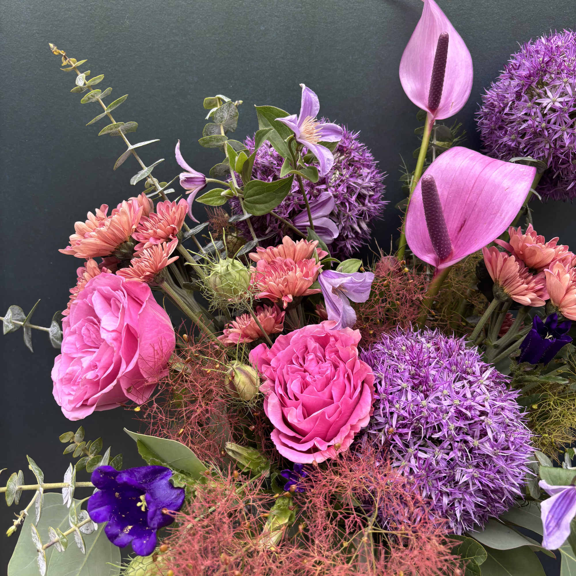 This design includes smoke bush, allium, and clematis, a moody and modern