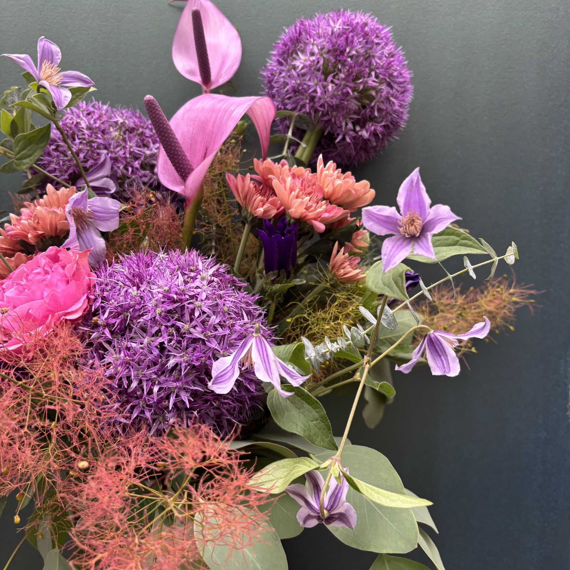 This design includes smoke bush, allium, and clematis, a moody and modern