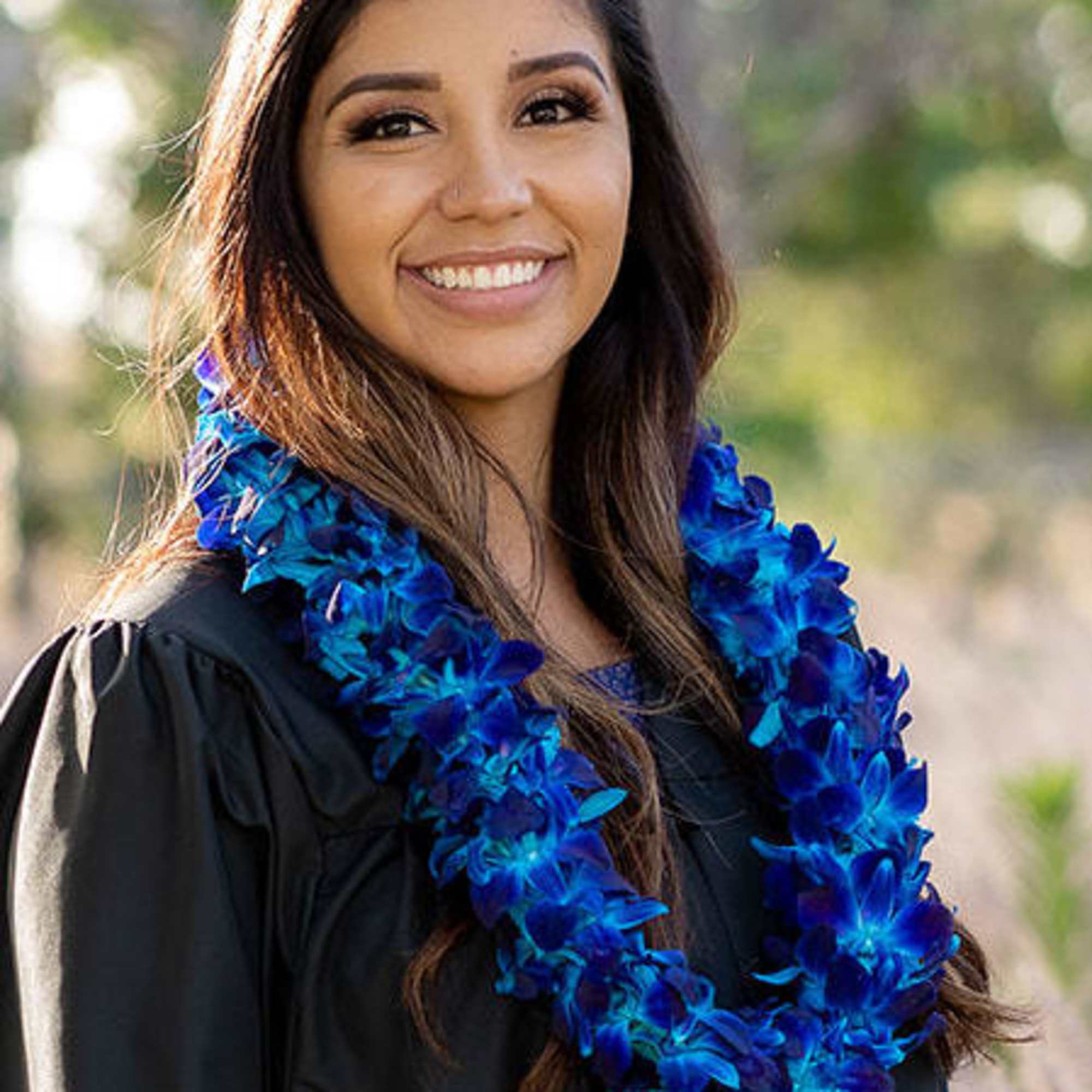 Woman in a black gown wearing a blue flower lei