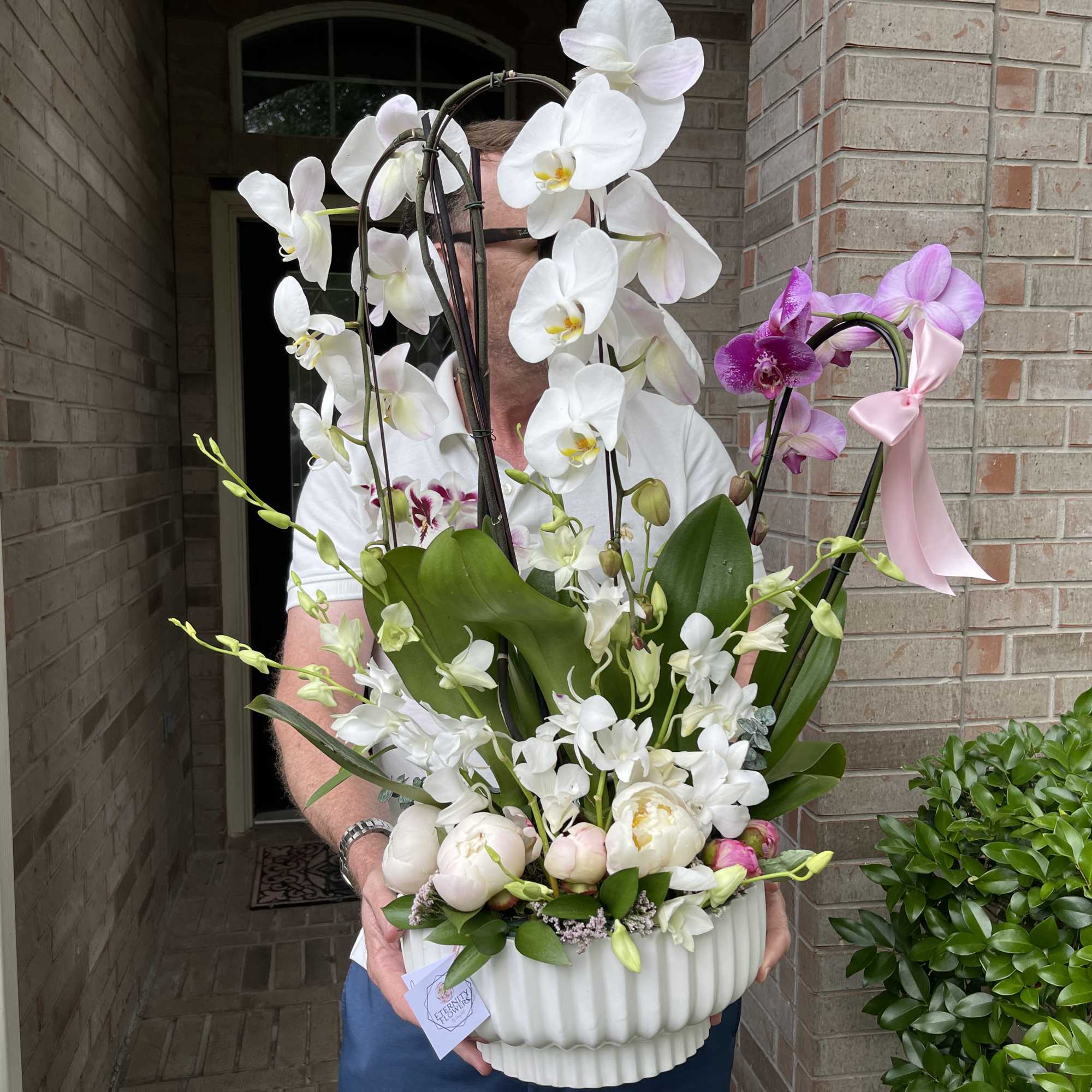 White and purple orchids arranged in a white ribbed vase