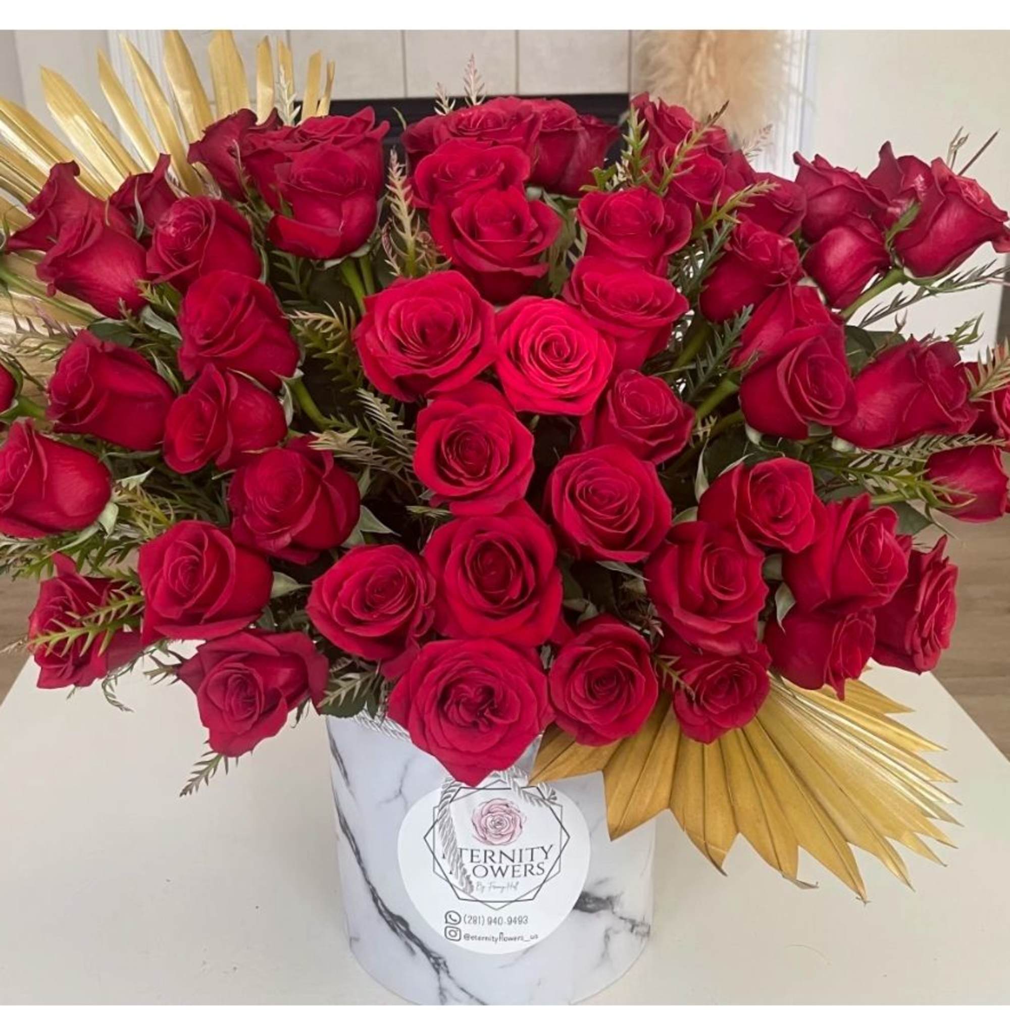 Large bouquet of red roses in a marble-patterned vase with gold accents