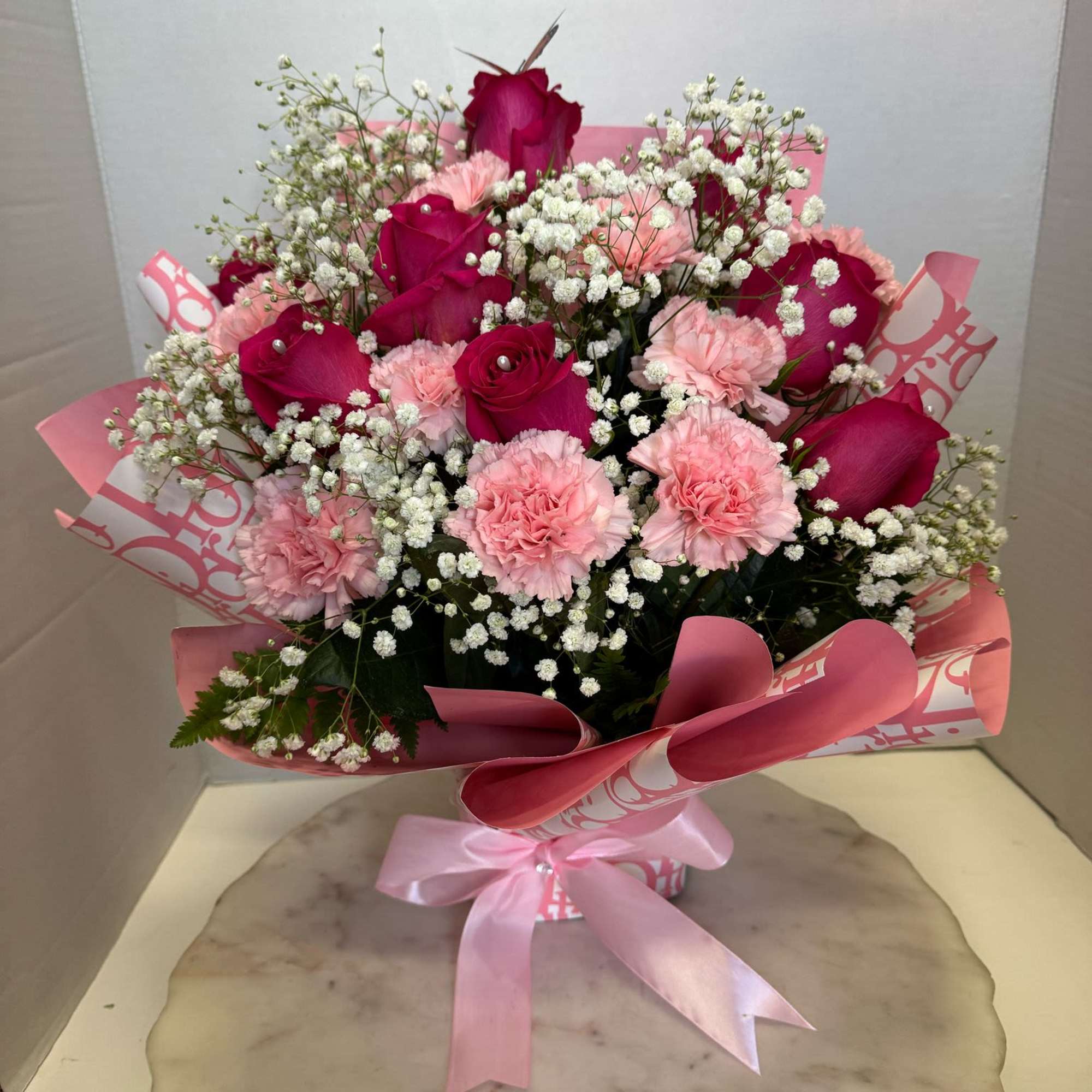 Pink roses and carnations with baby's breath in a wrapped bouquet