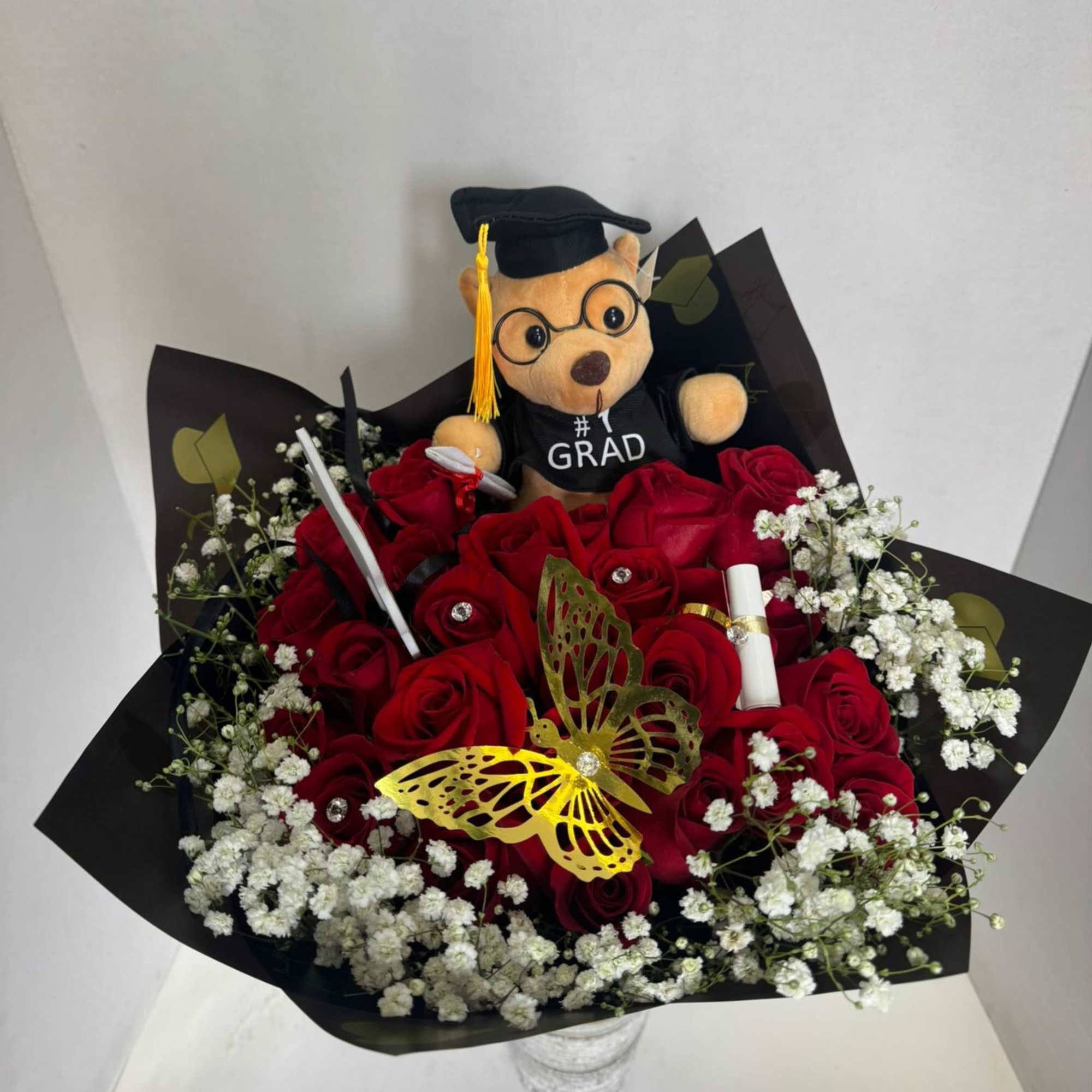 Red rose bouquet with baby’s breath and a graduation teddy bear topper