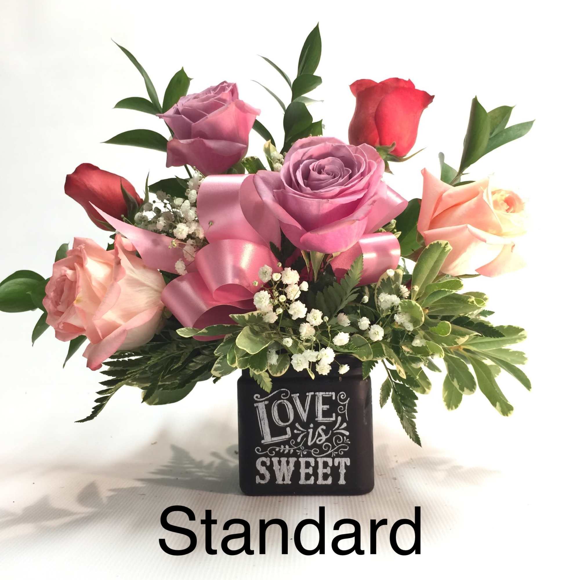 Pink and red roses in a black vase with a "Love is Sweet" design