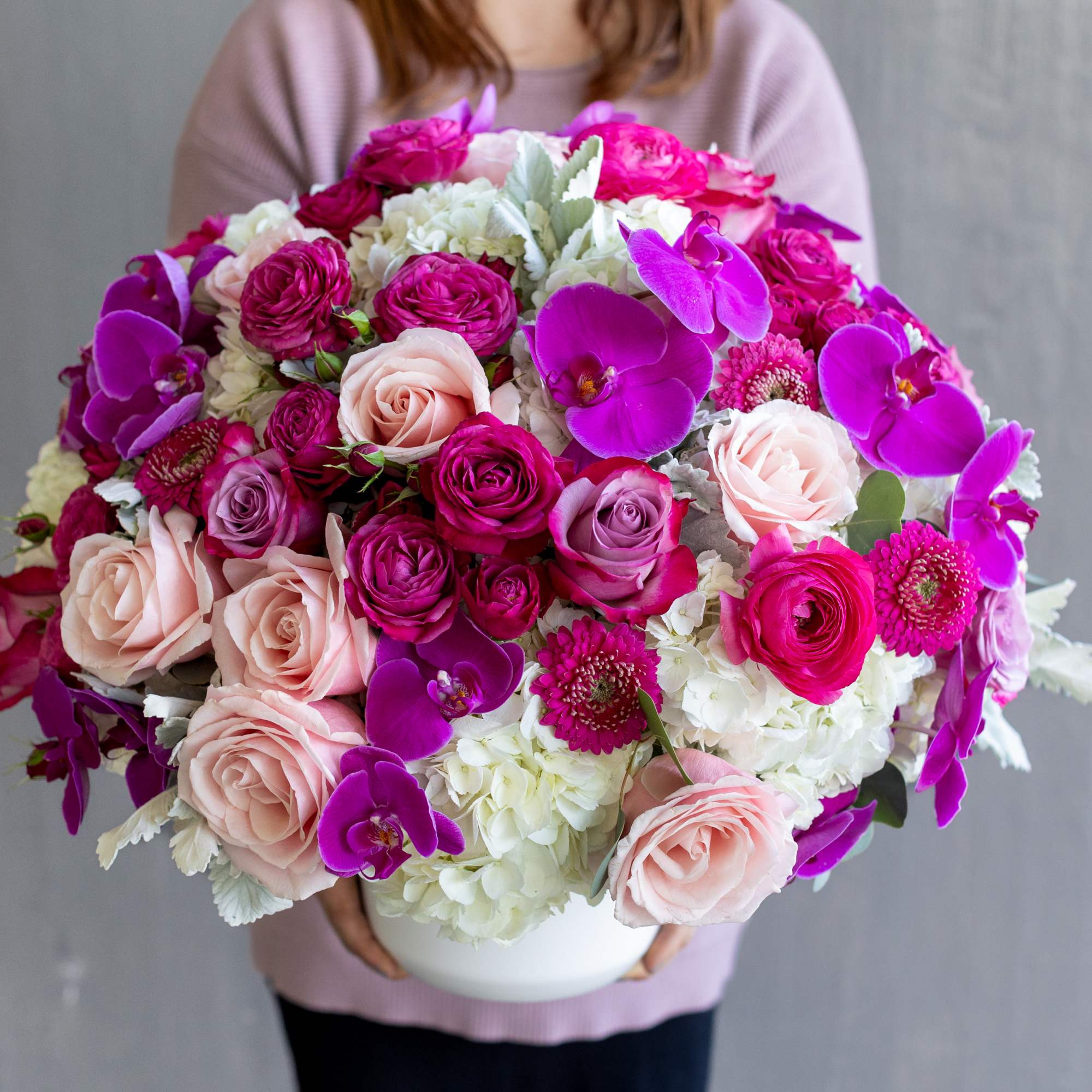 Large bouquet of pink roses and purple orchids in a white vase