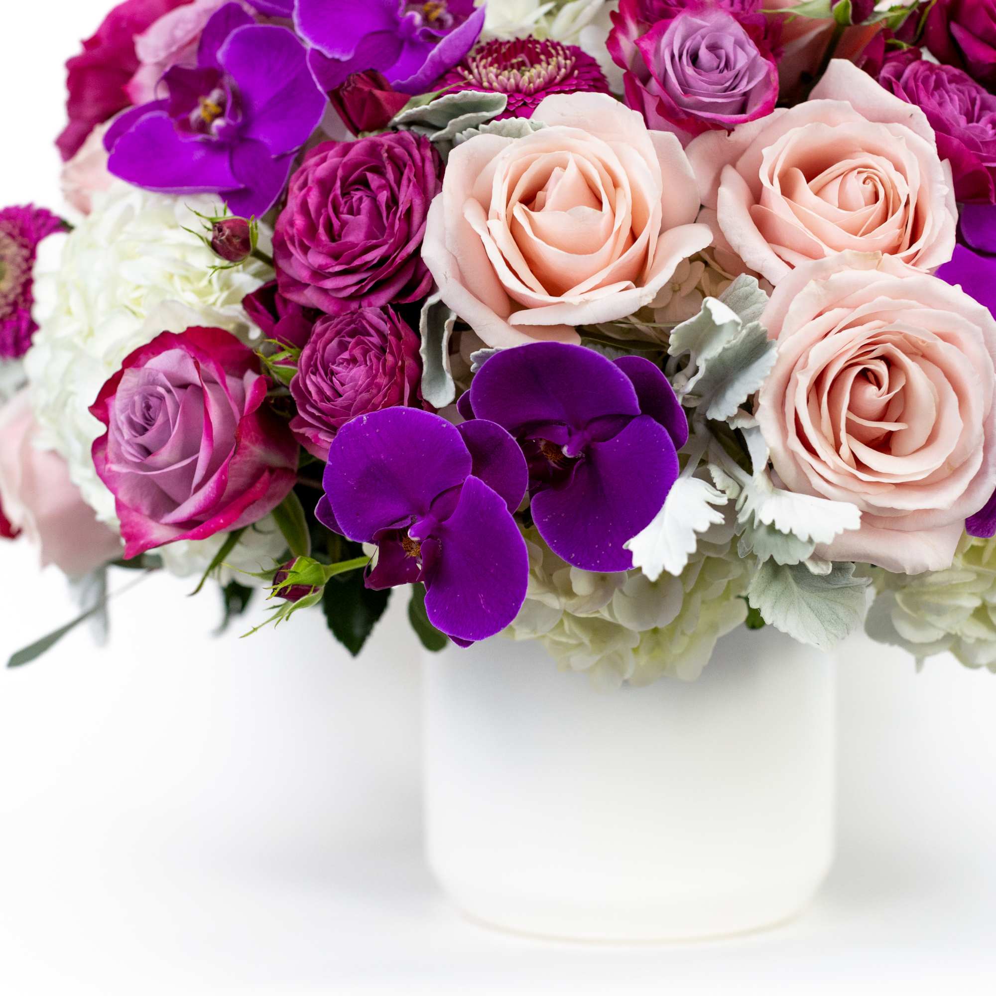 Pink and purple roses with orchids in a white vase