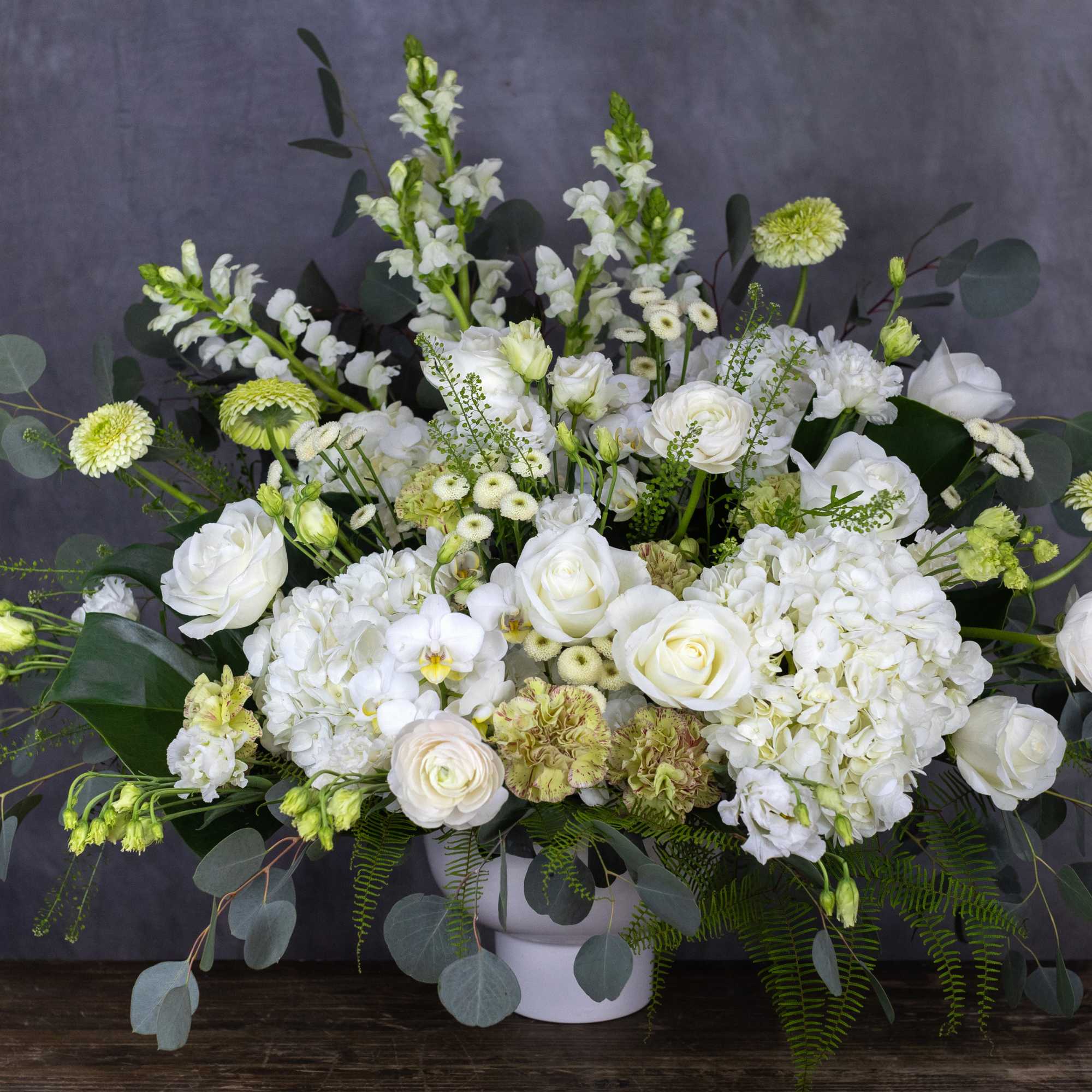 White floral arrangement in a white vase with eucalyptus