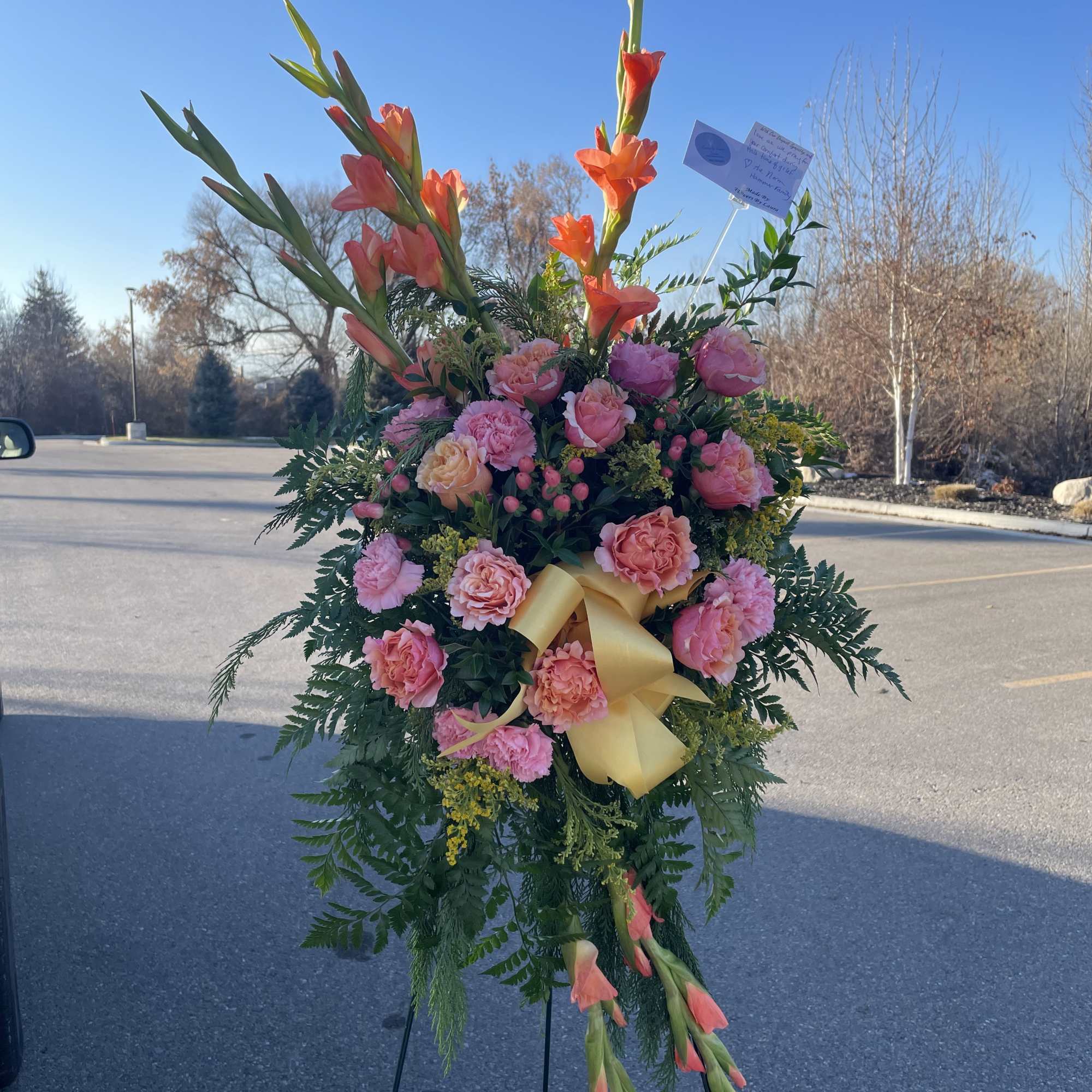 Standing floral spray with pink roses and orange gladiolus on an easel
