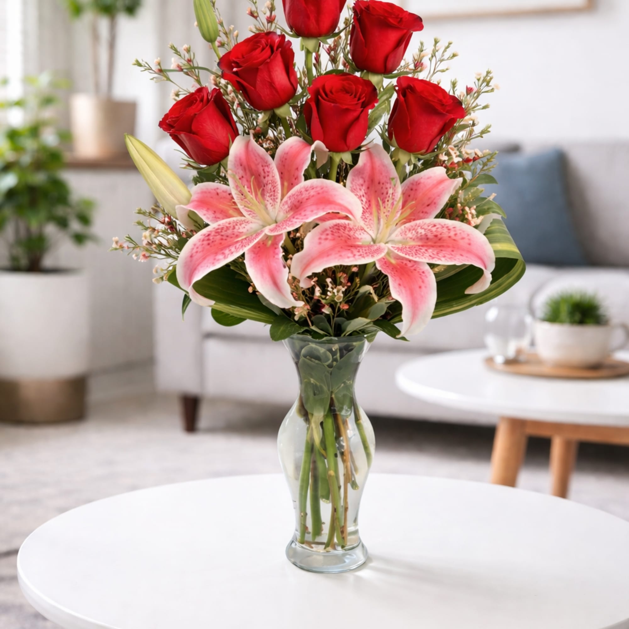 Red roses and pink lilies arranged in a clear glass vase