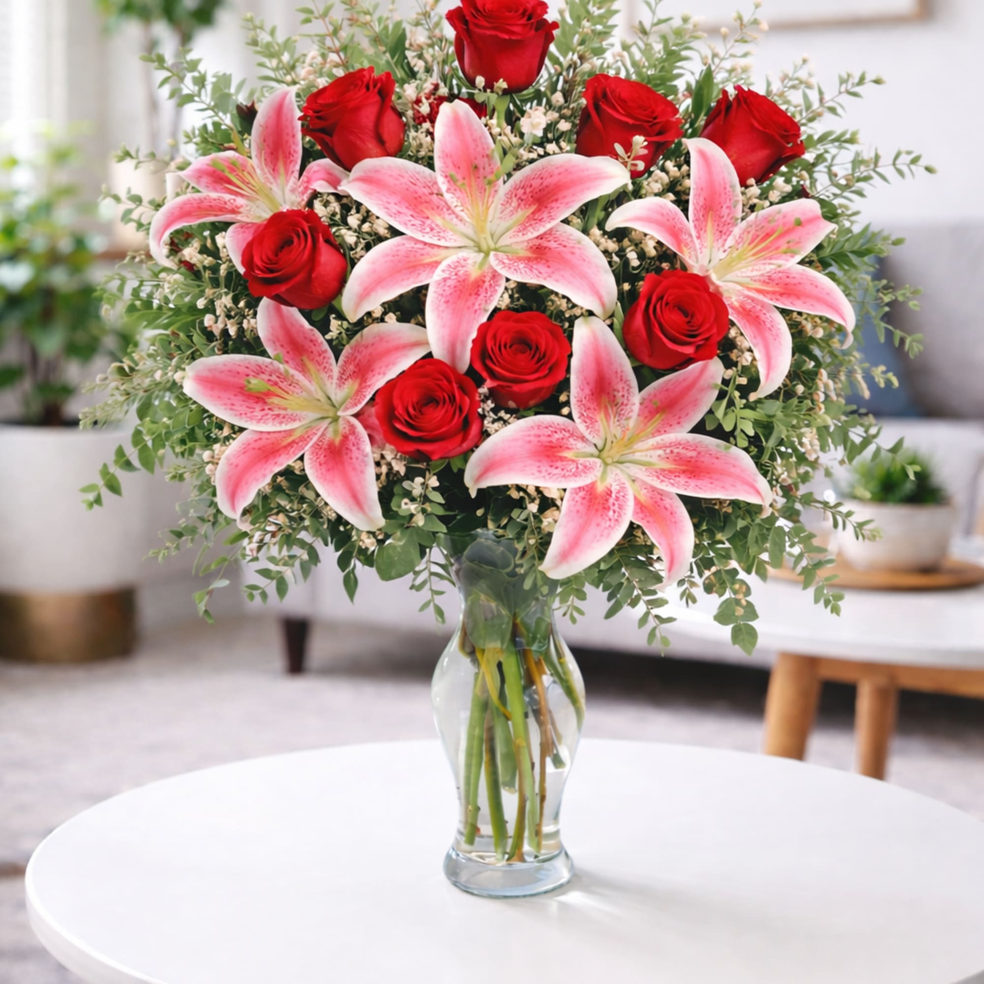 Bouquet of red roses and pink lilies in a clear glass vase