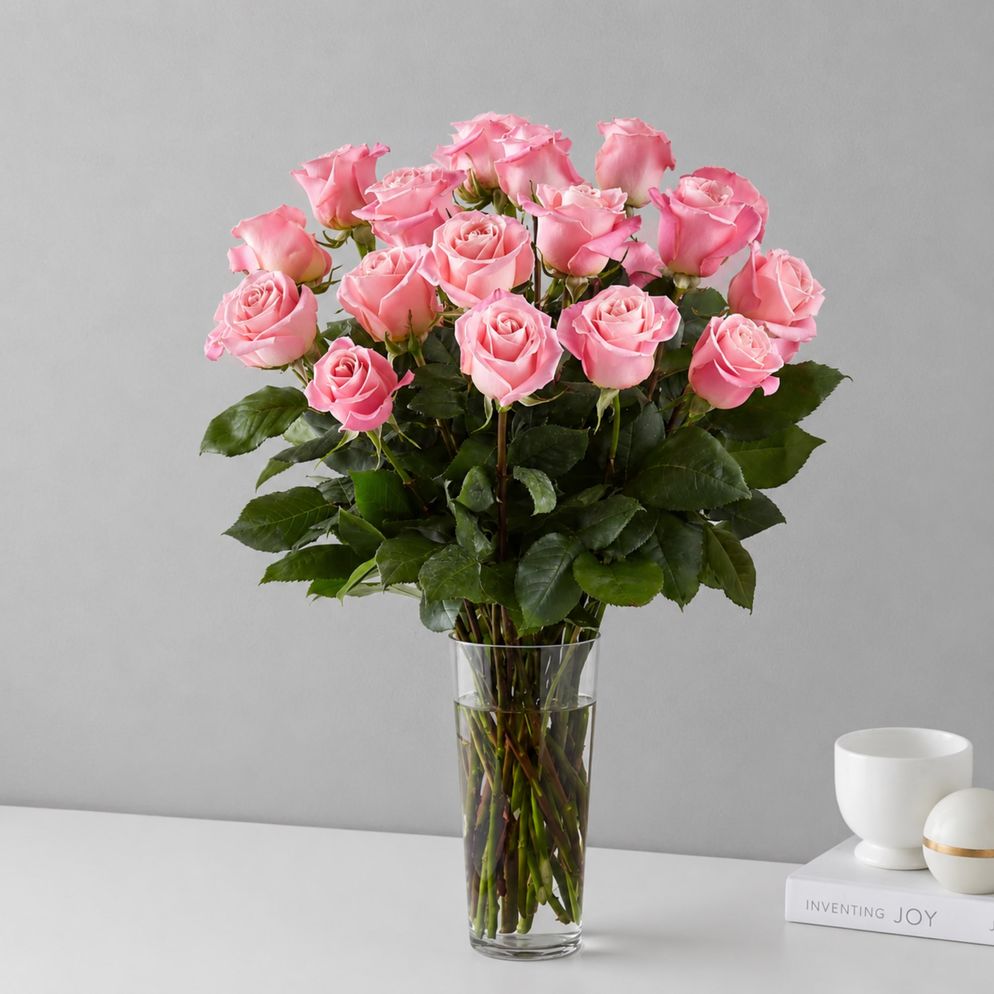 Soft pink roses gathered tall in a clear glass vase create a