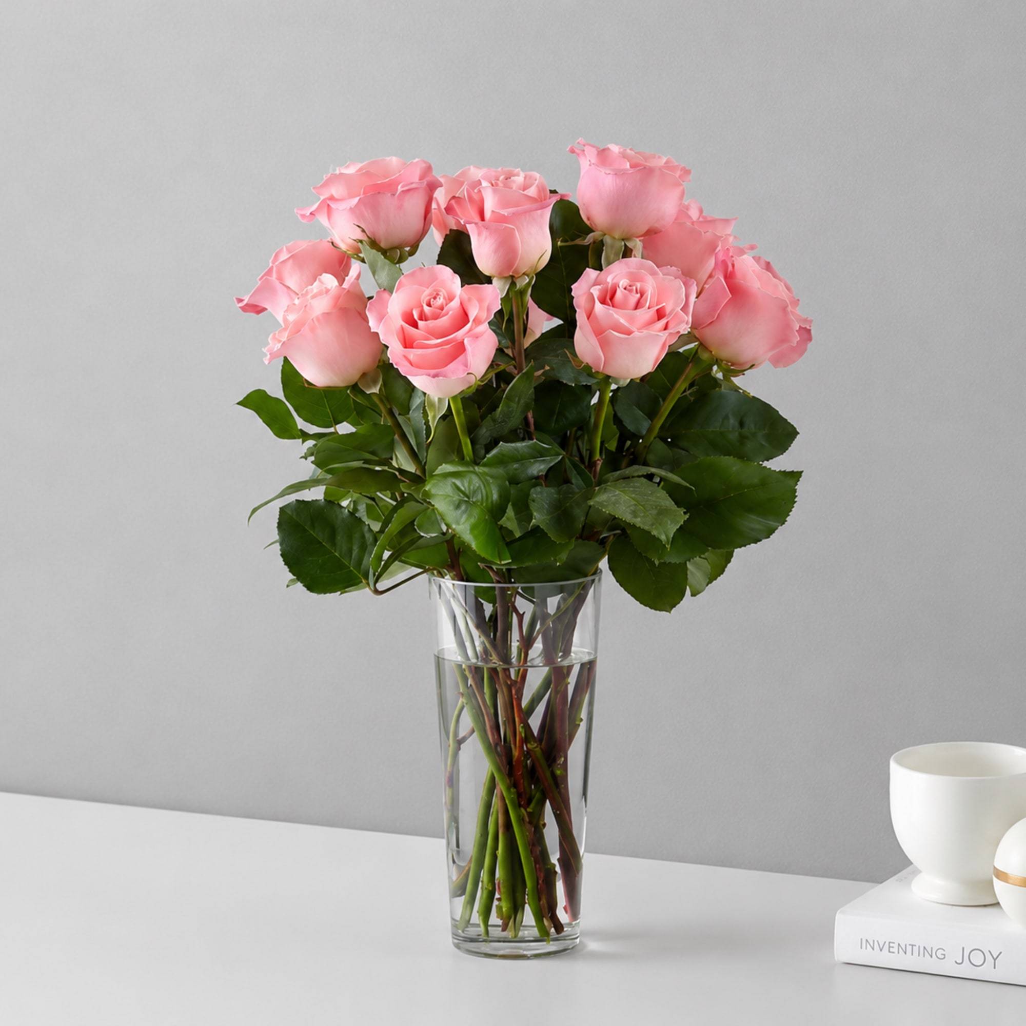 Soft pink roses gathered tall in a clear glass vase create a