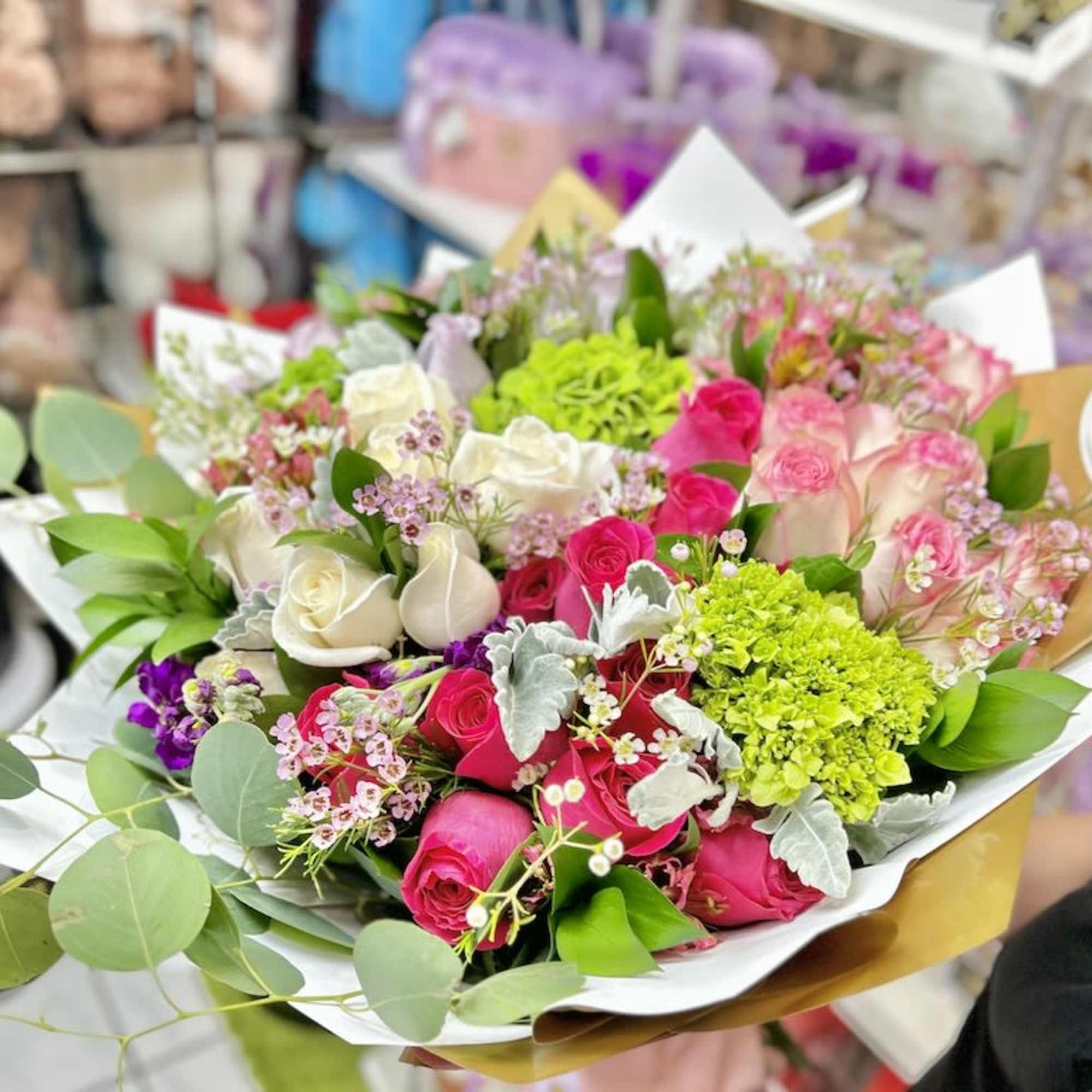 Mixed bouquet of hot pink and ivory roses with lime green blooms in white and gold wrapping