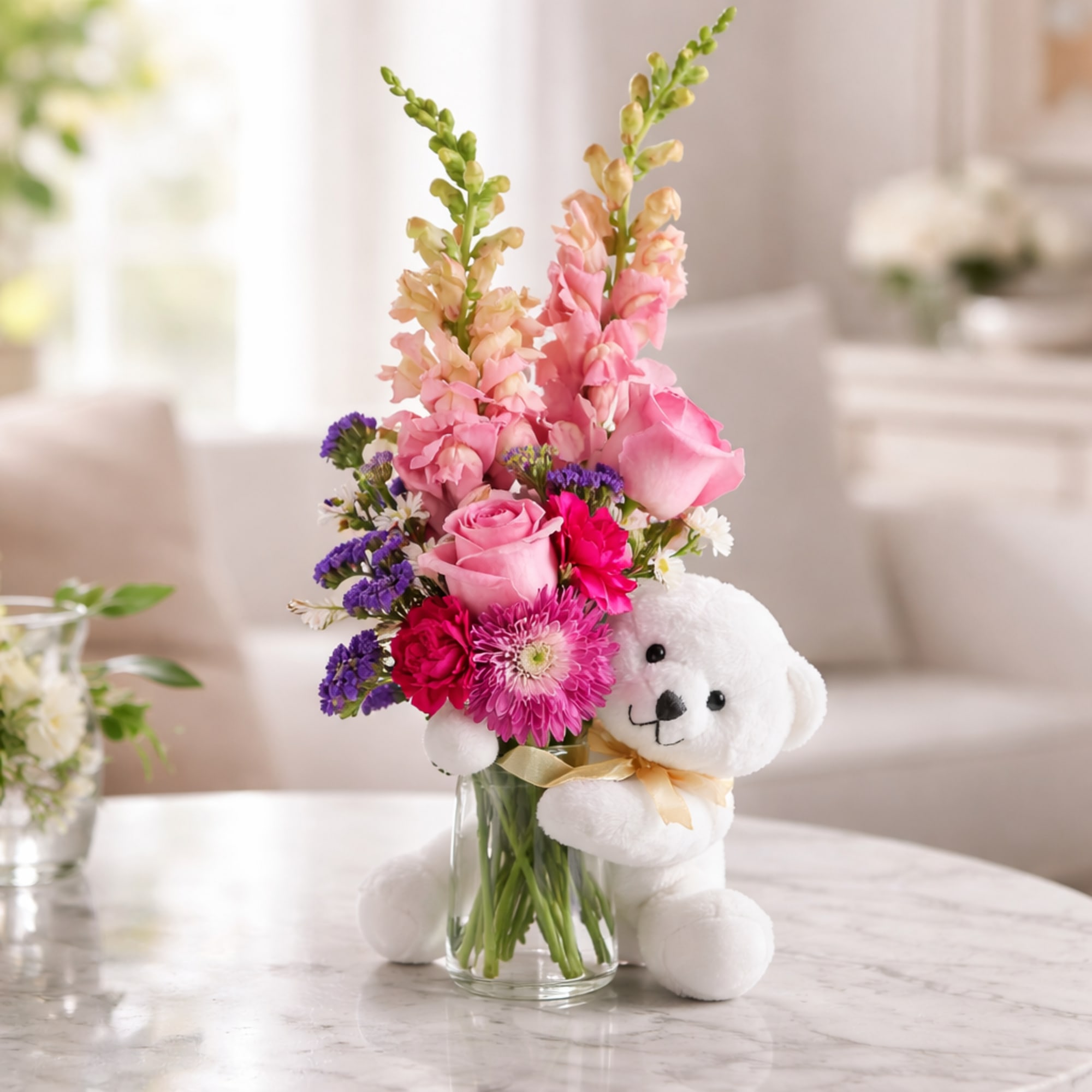 Pink and purple flower arrangement in a glass vase with a white teddy bear