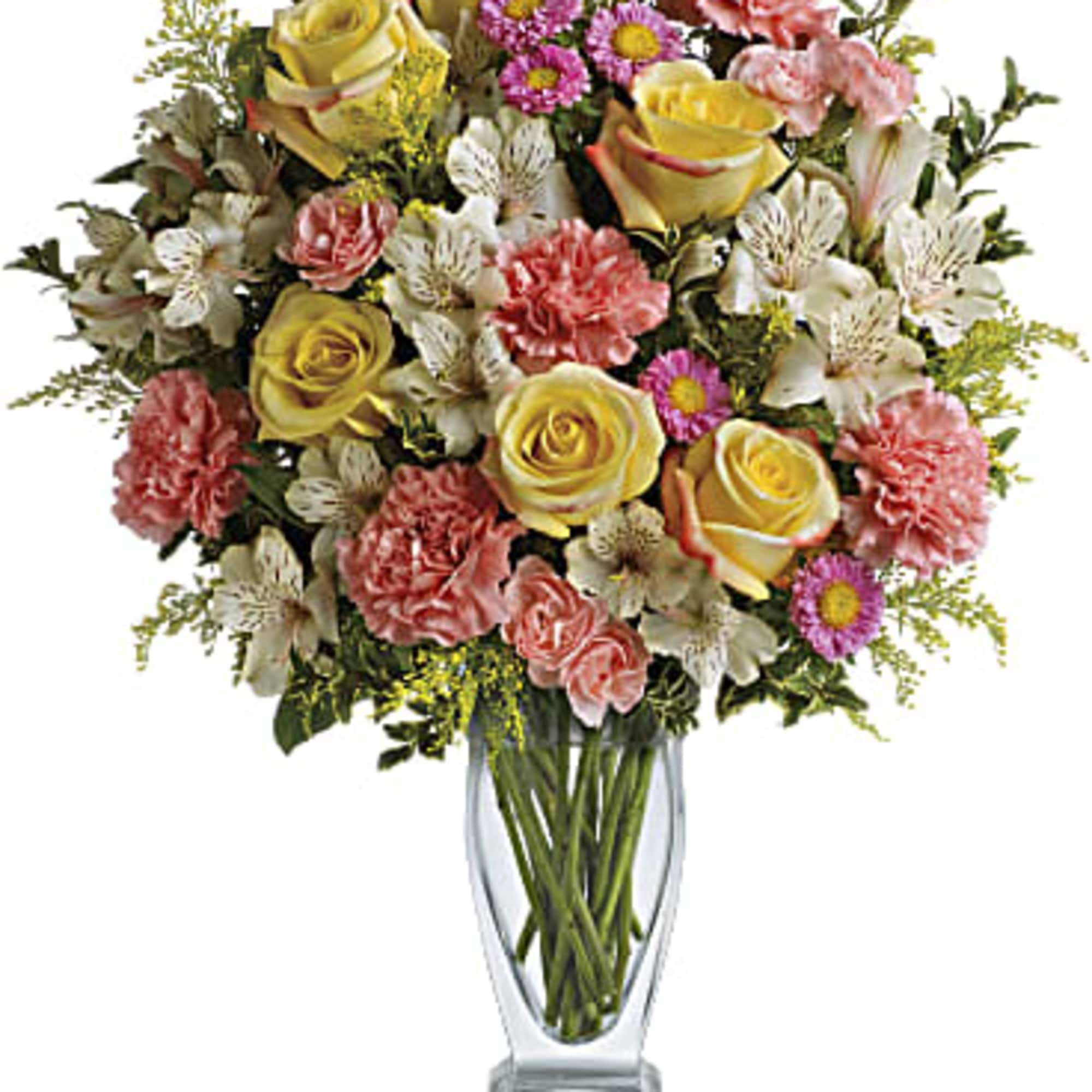 Mixed bouquet of yellow roses, pink carnations, and daisies in a clear glass vase