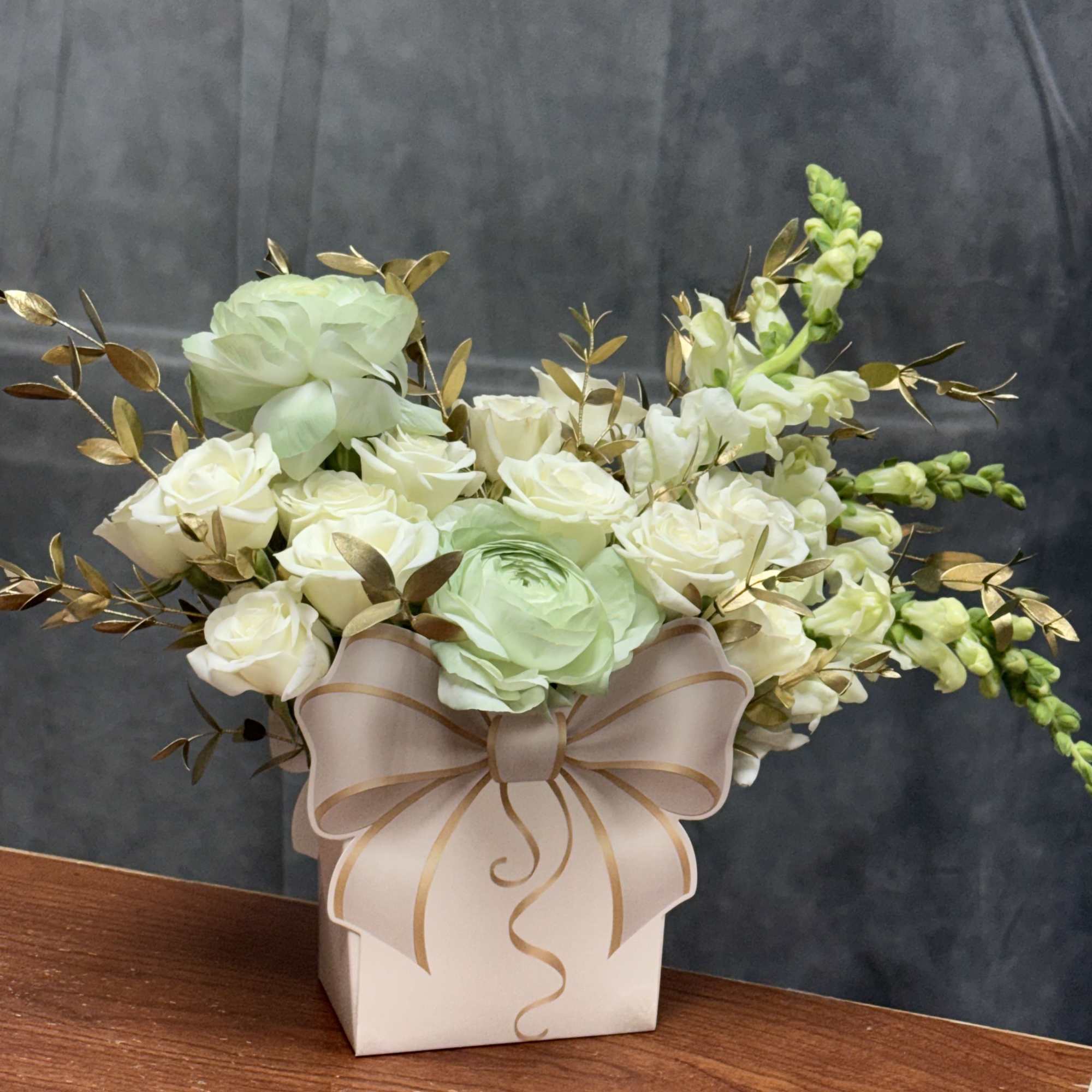 A luxurious blend of white blooms, soft green ranunculus , and gold-tinted