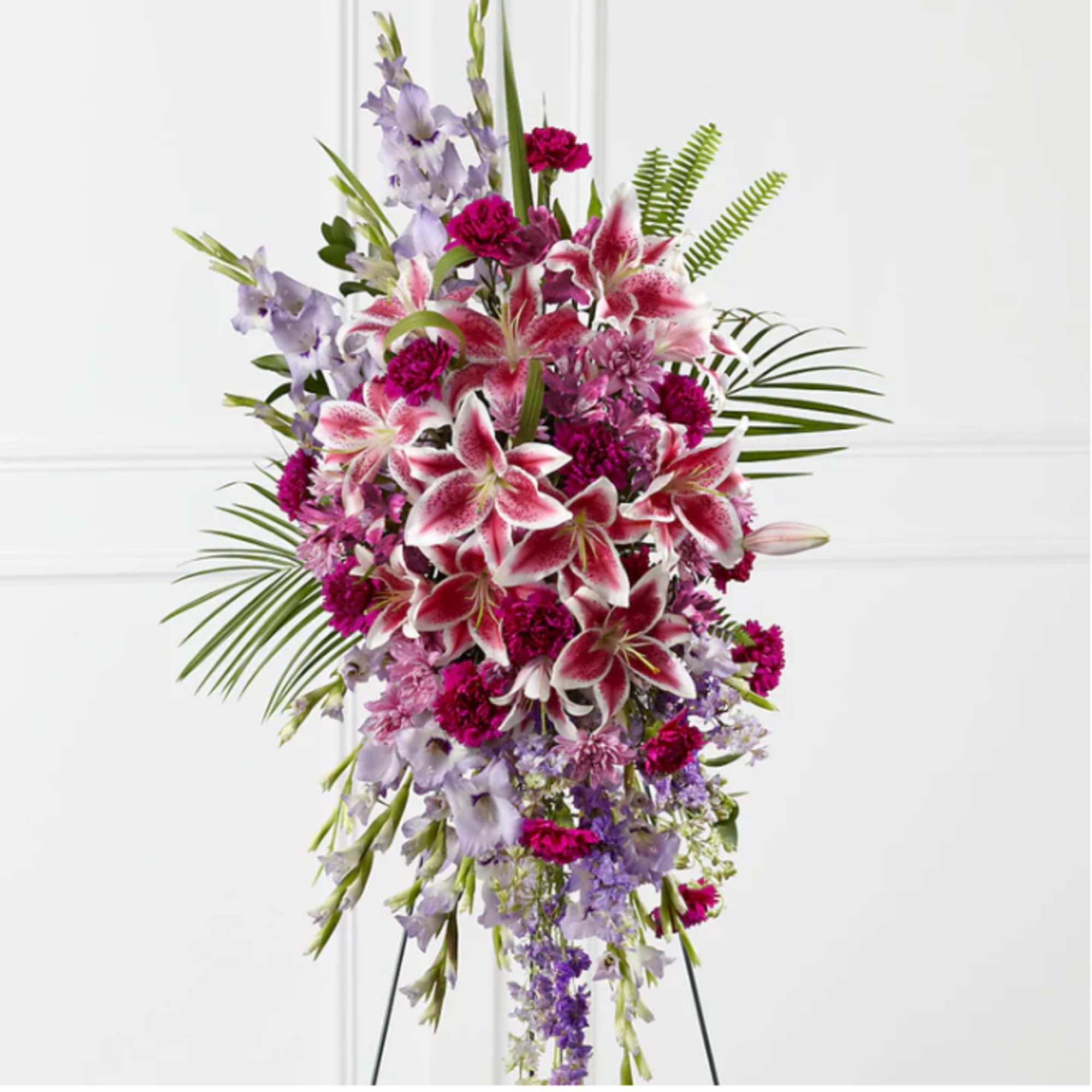 Tall standing spray of pink lilies and purple flowers on an easel