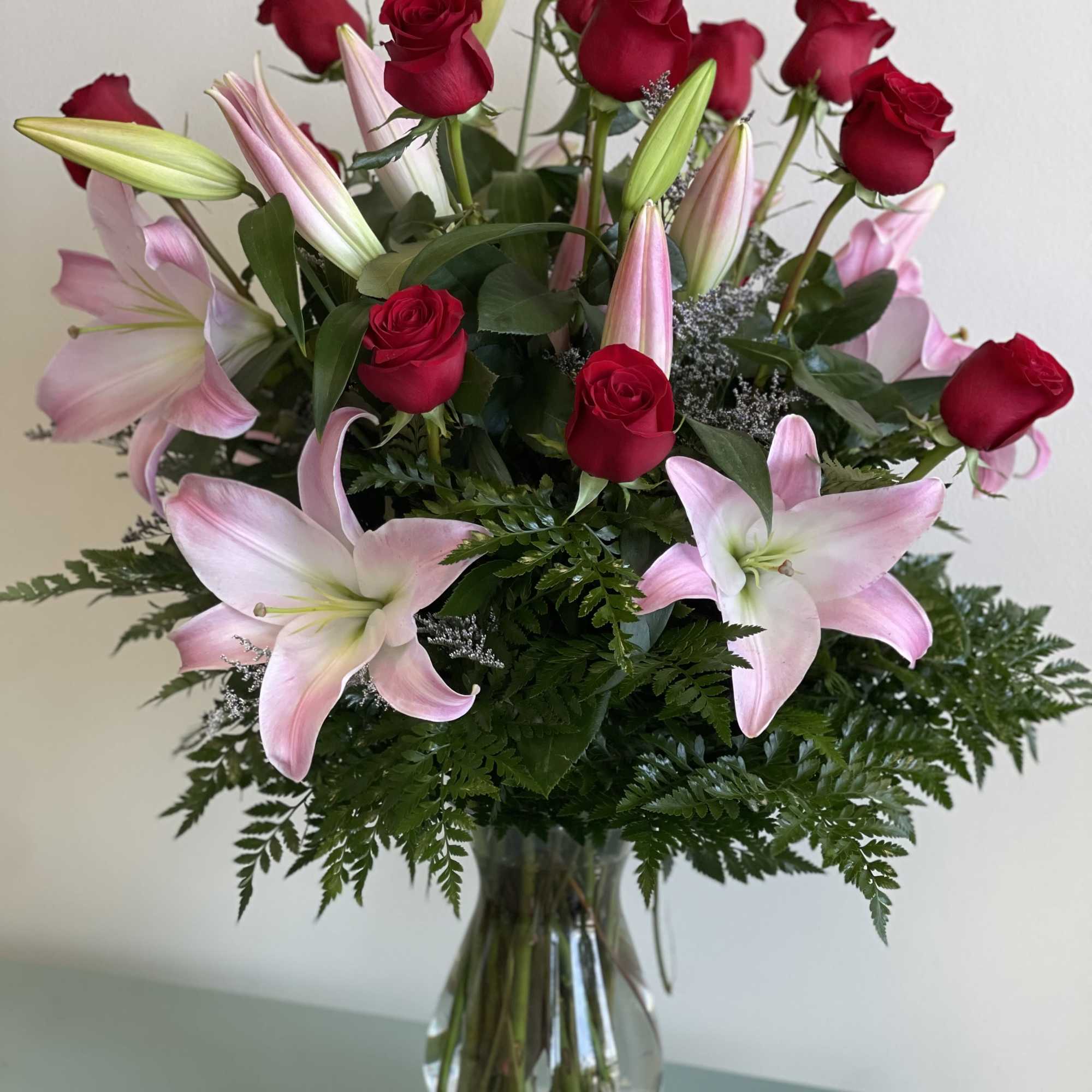 Red roses and pink lilies arranged in a clear glass vase
