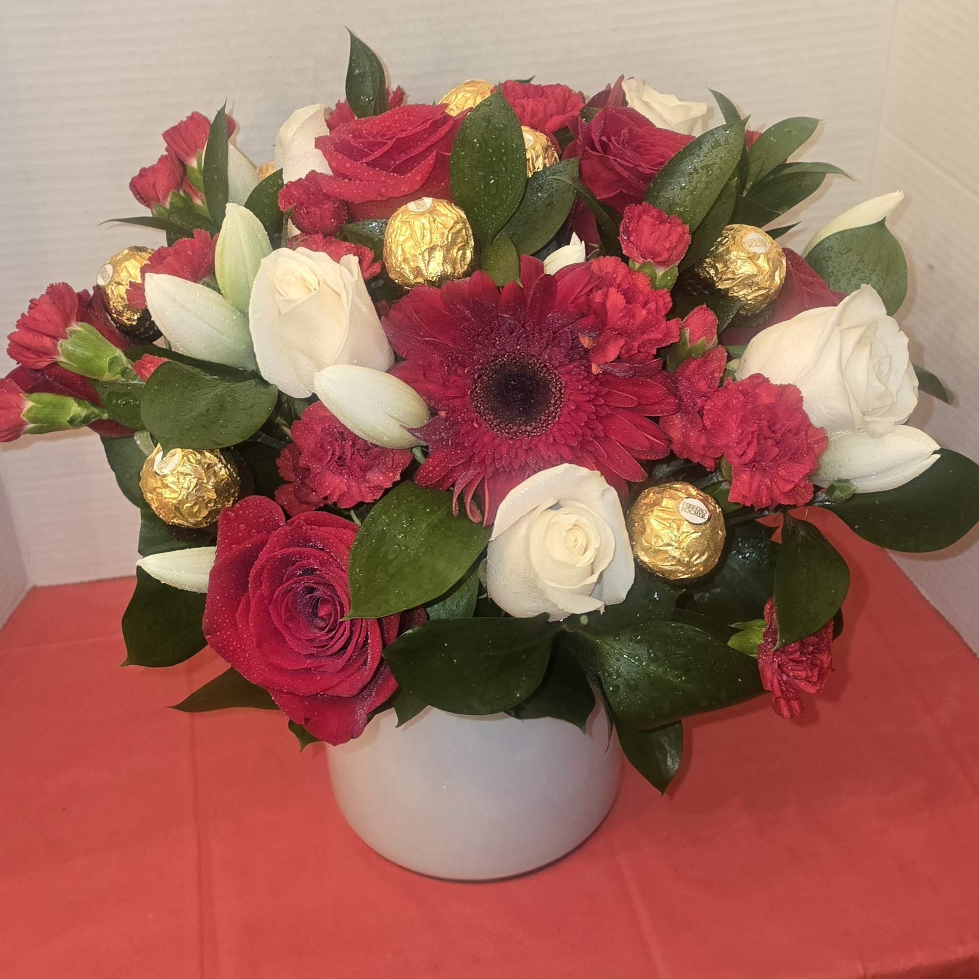 Bouquet of red and white roses with gerbera daisies in a white vase