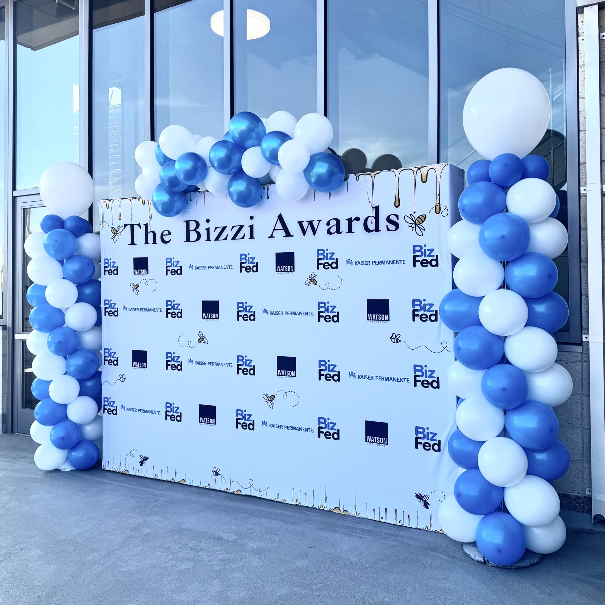 Blue and white balloon columns framing a Bizzi Awards backdrop